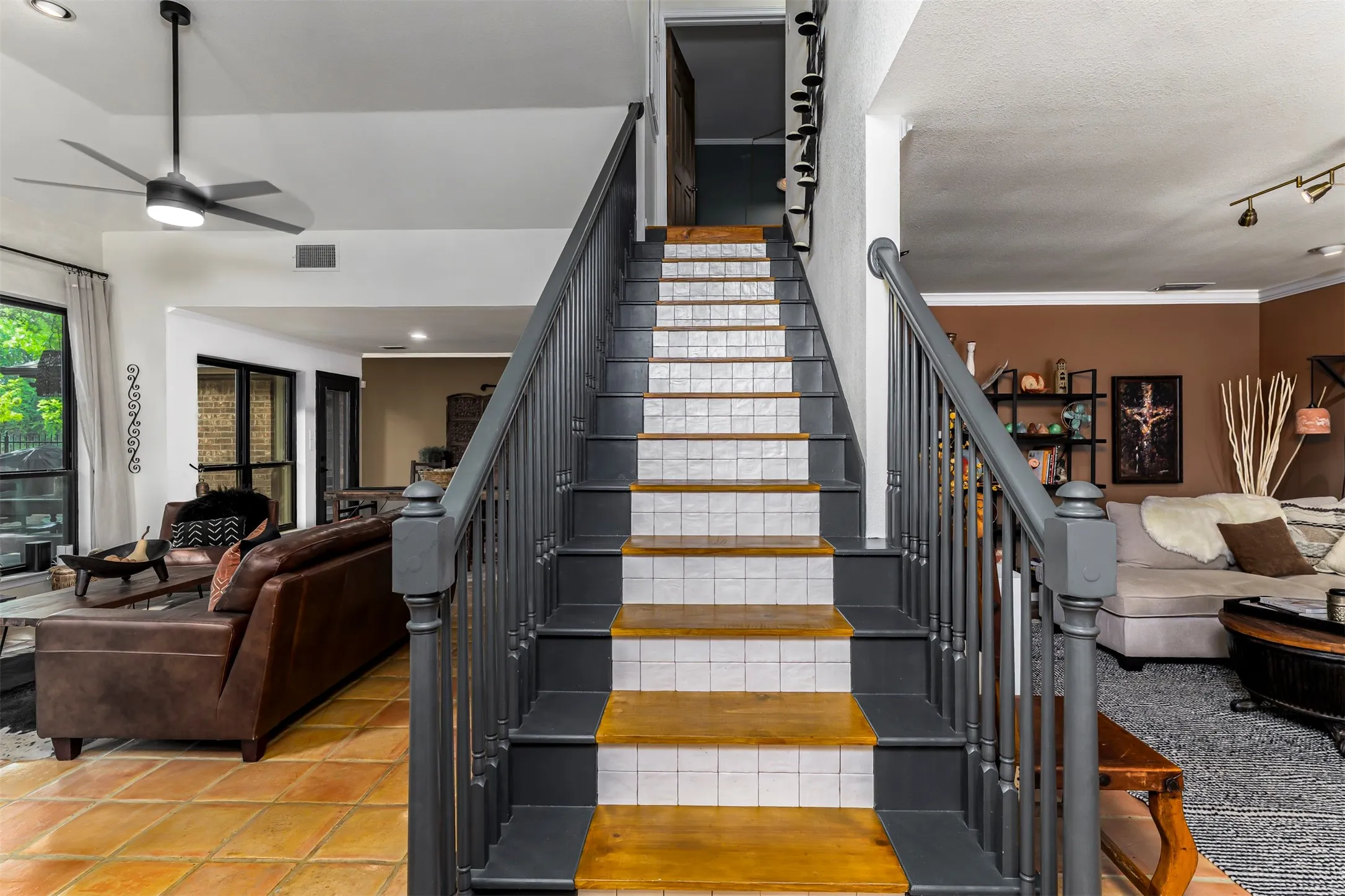 Central staircase with dark metal railings, white subway tile treads, and wood-finish stringers creates a striking architectural focal point