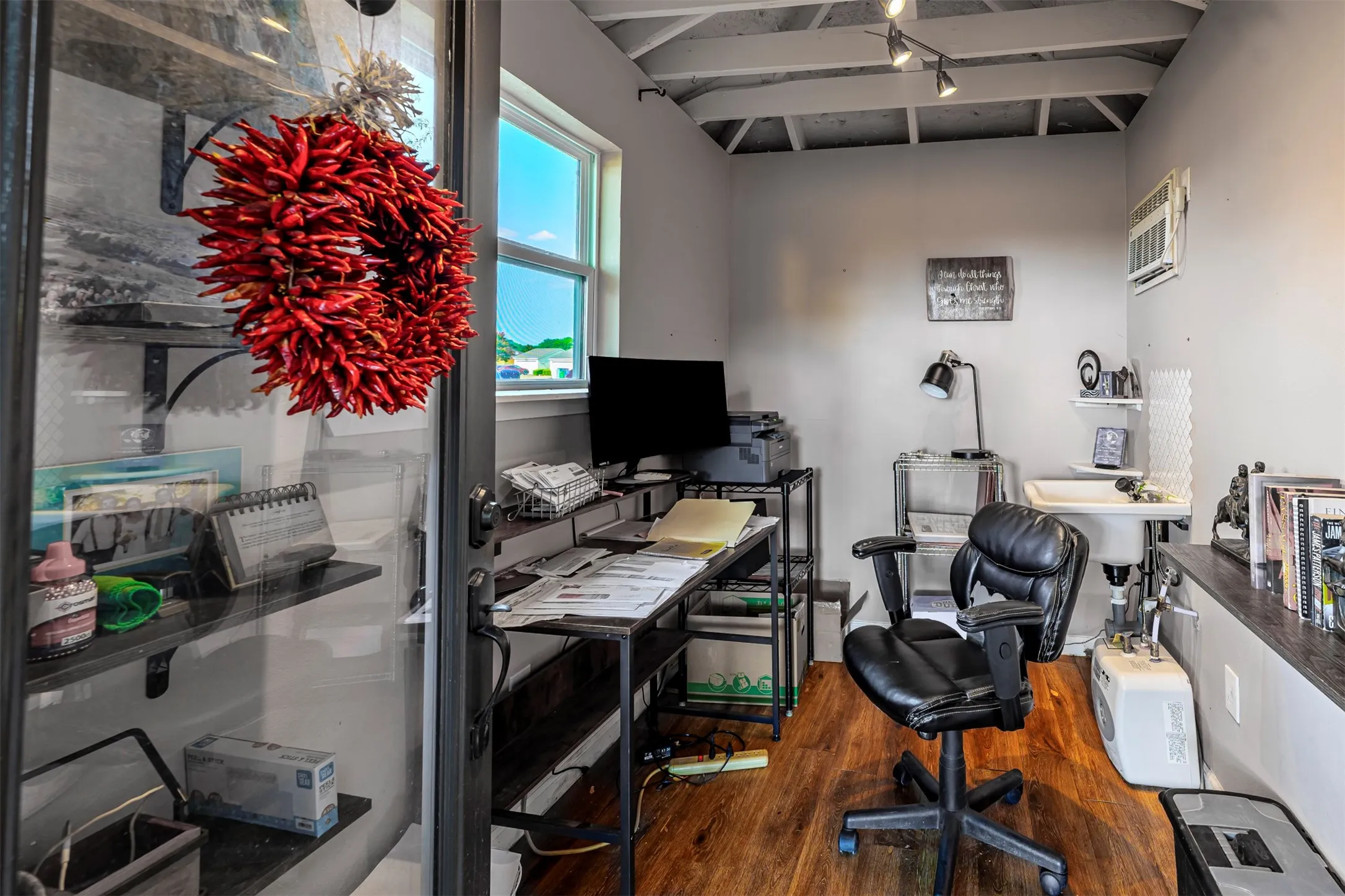 Dedicated home office featuring wood-finish flooring, built-in wall shelving and cabinetry, track lighting, and a black ergonomic desk chair