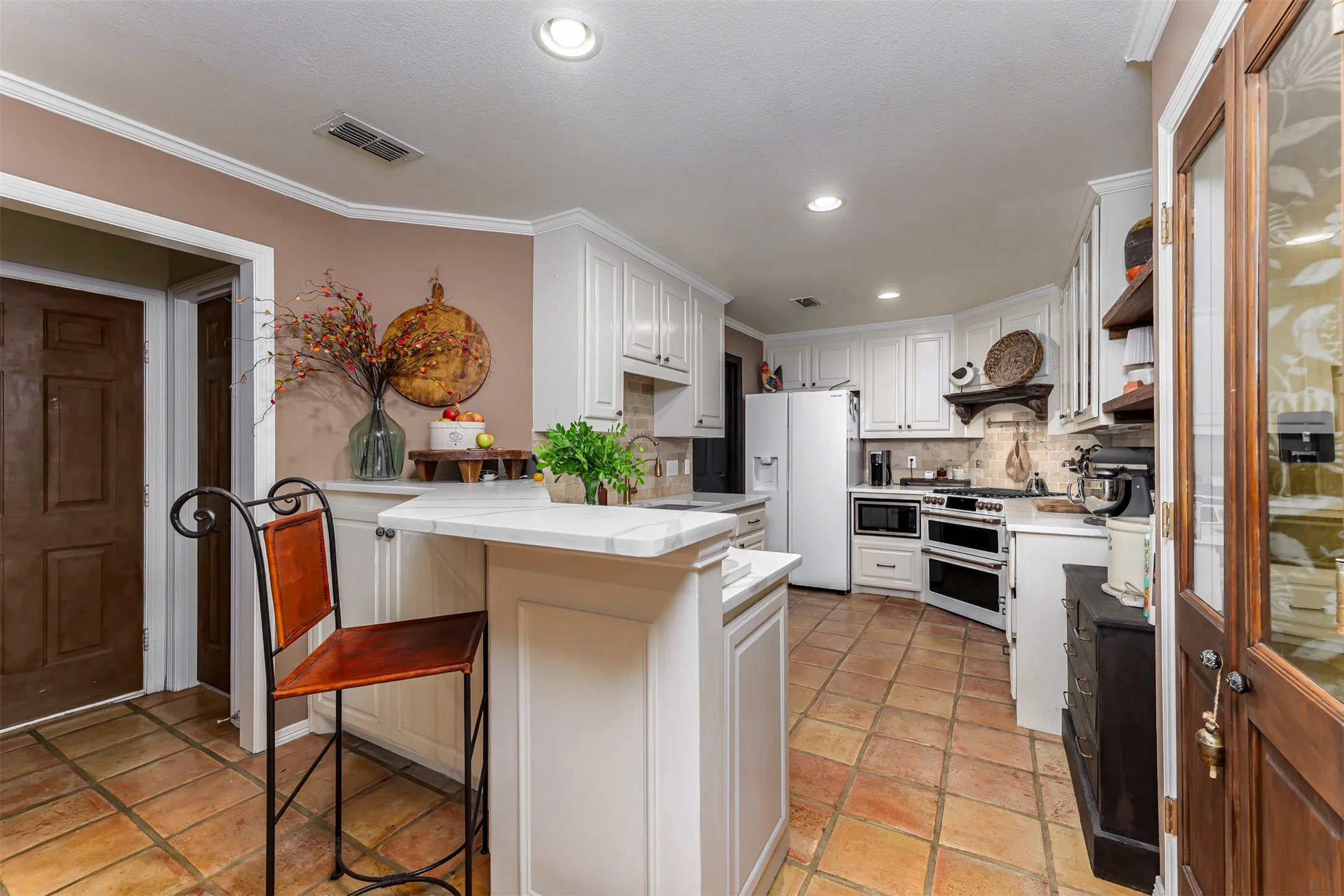 Elegant kitchen featuring white cabinetry, stainless steel appliances, and a large center island with seating