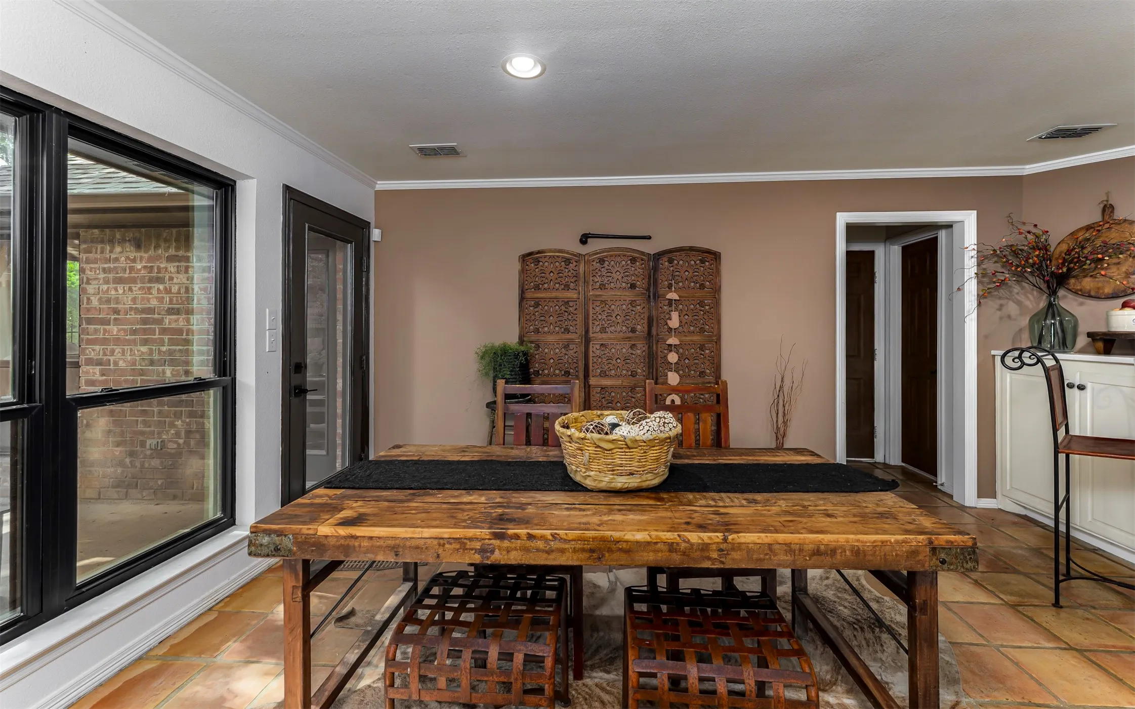 Terracotta-style tile flooring, recessed lighting, crown molding, and a solid-panel door with glass inserts