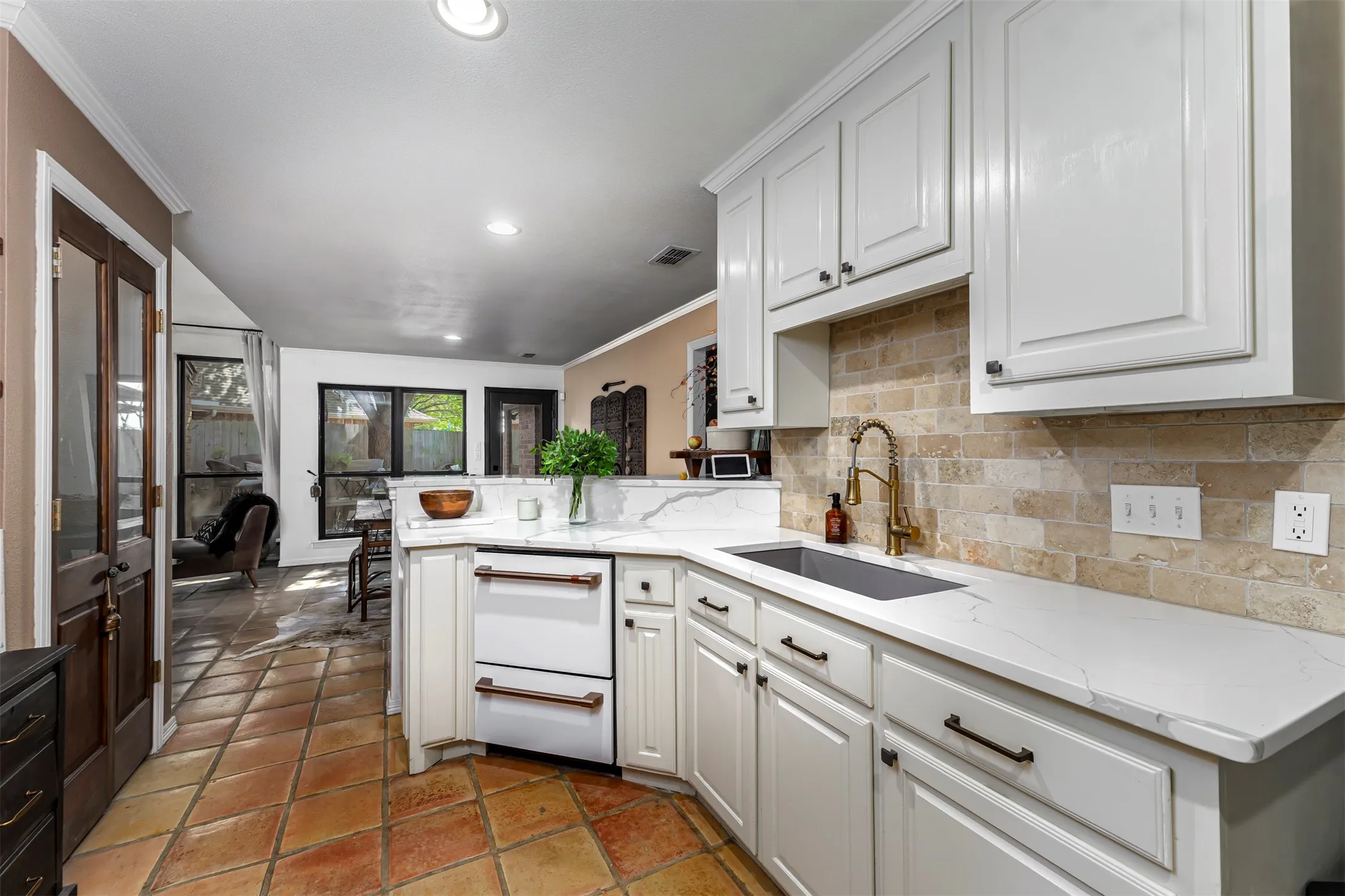 Bright, chef-ready kitchen featuring white cabinetry with brushed metal hardware, white subway tile backsplash, quartz countertops, and stainless steel appliances including a gas range