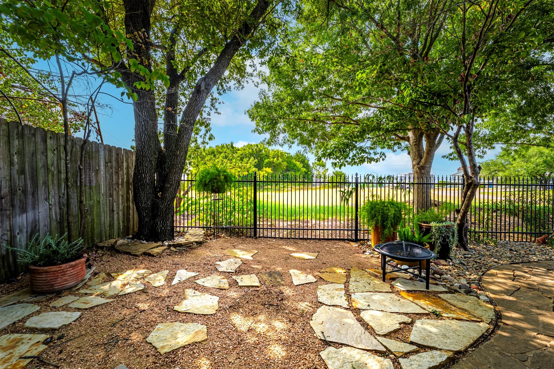 Mature trees, flagstone patio, gravel ground cover, and secure perimeter fencing