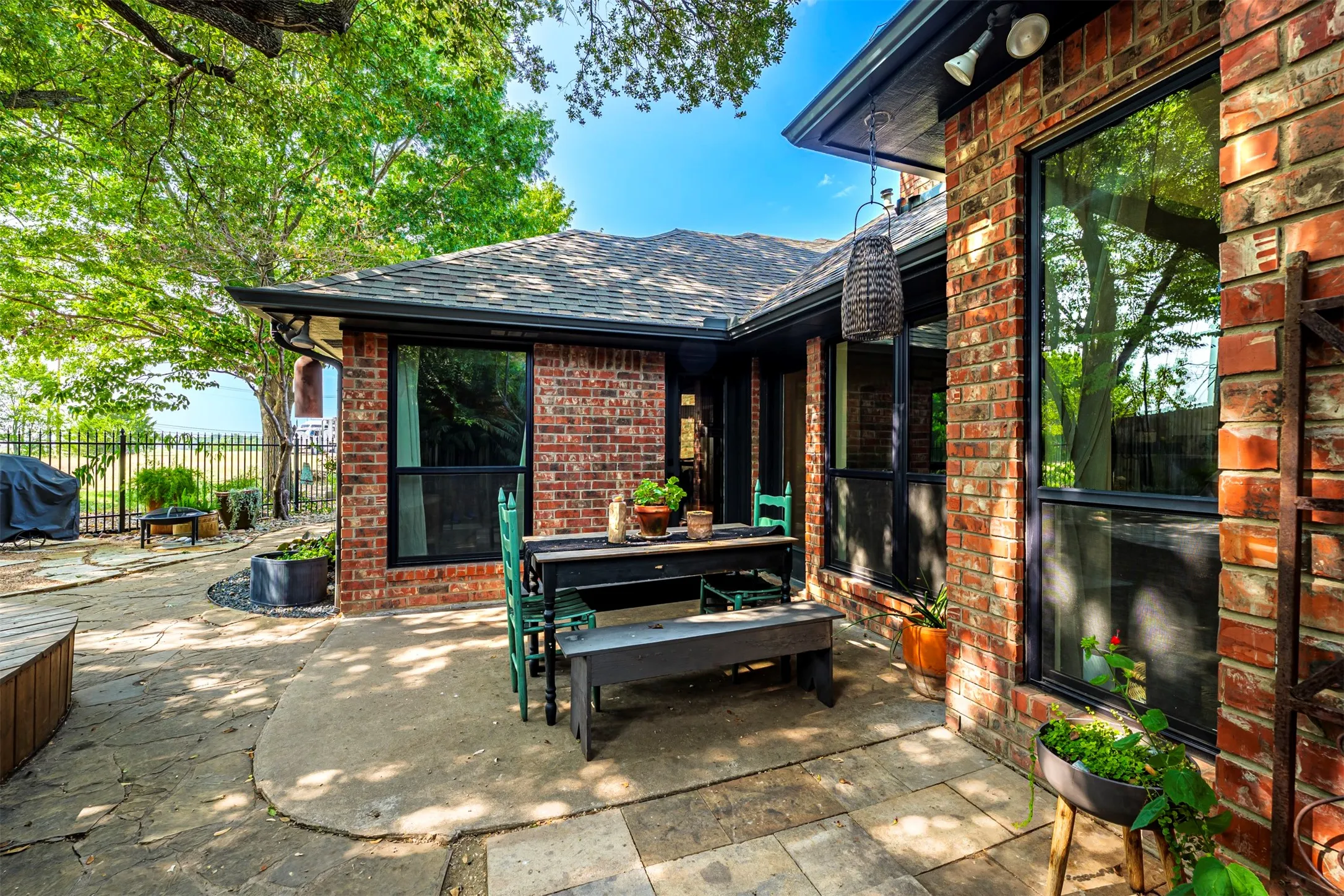 Brick exterior with a shingled roof, featuring large windows and a covered patio area