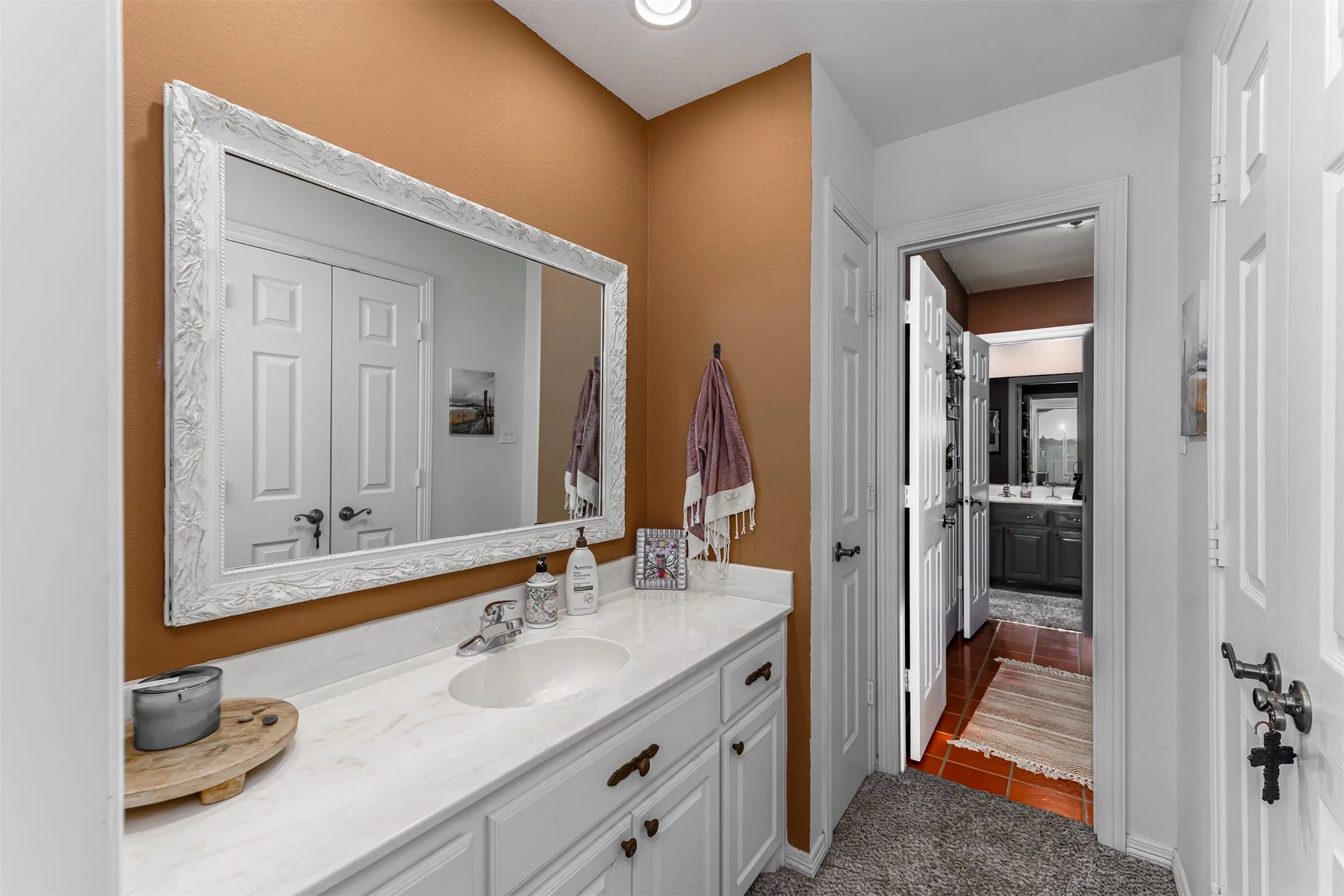 Master bathroom featuring a white framed mirror above a dual-sink vanity with white cabinetry and brushed nickel hardware