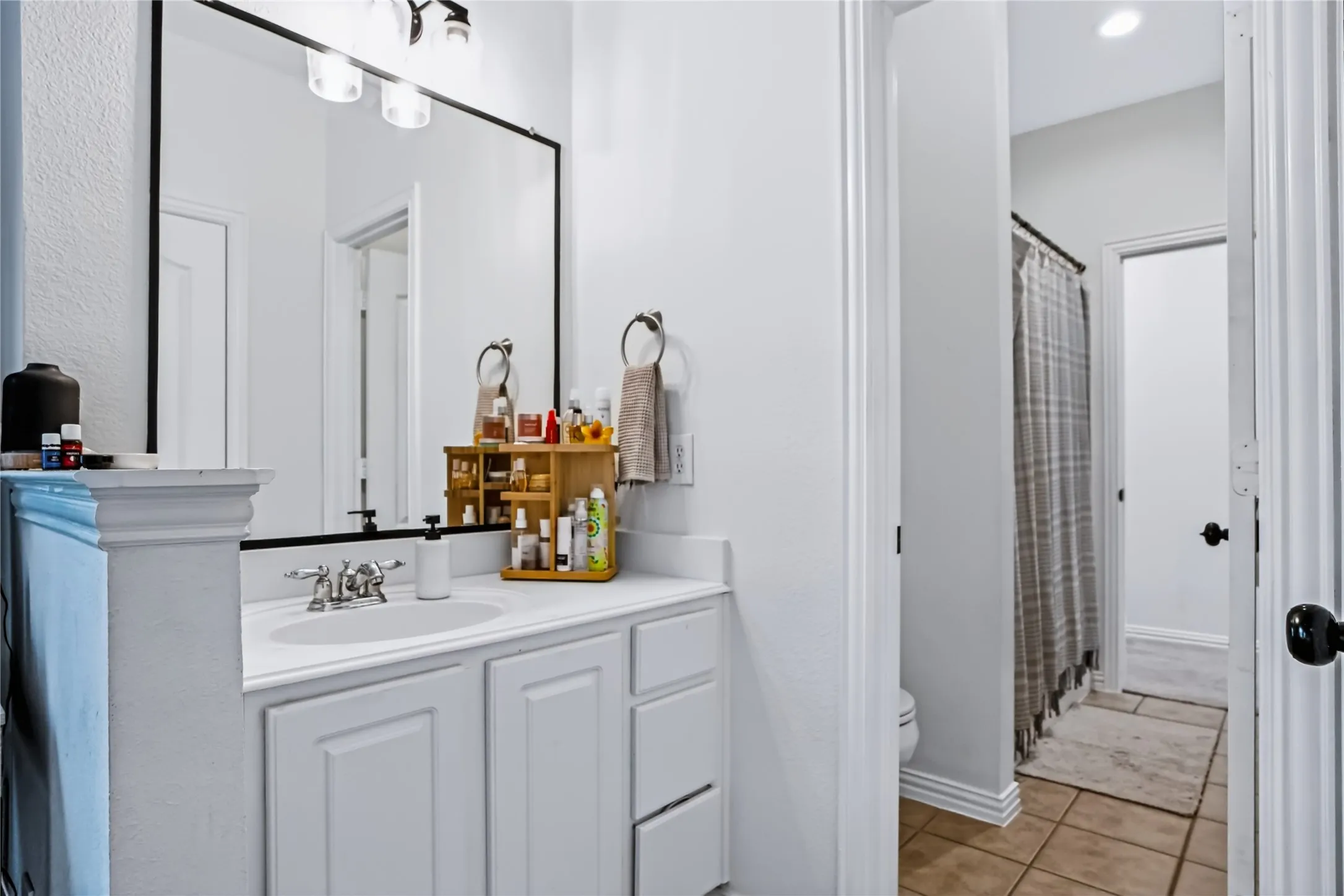 White vanity with integrated sink, chrome faucet, and rectangular black-framed mirror