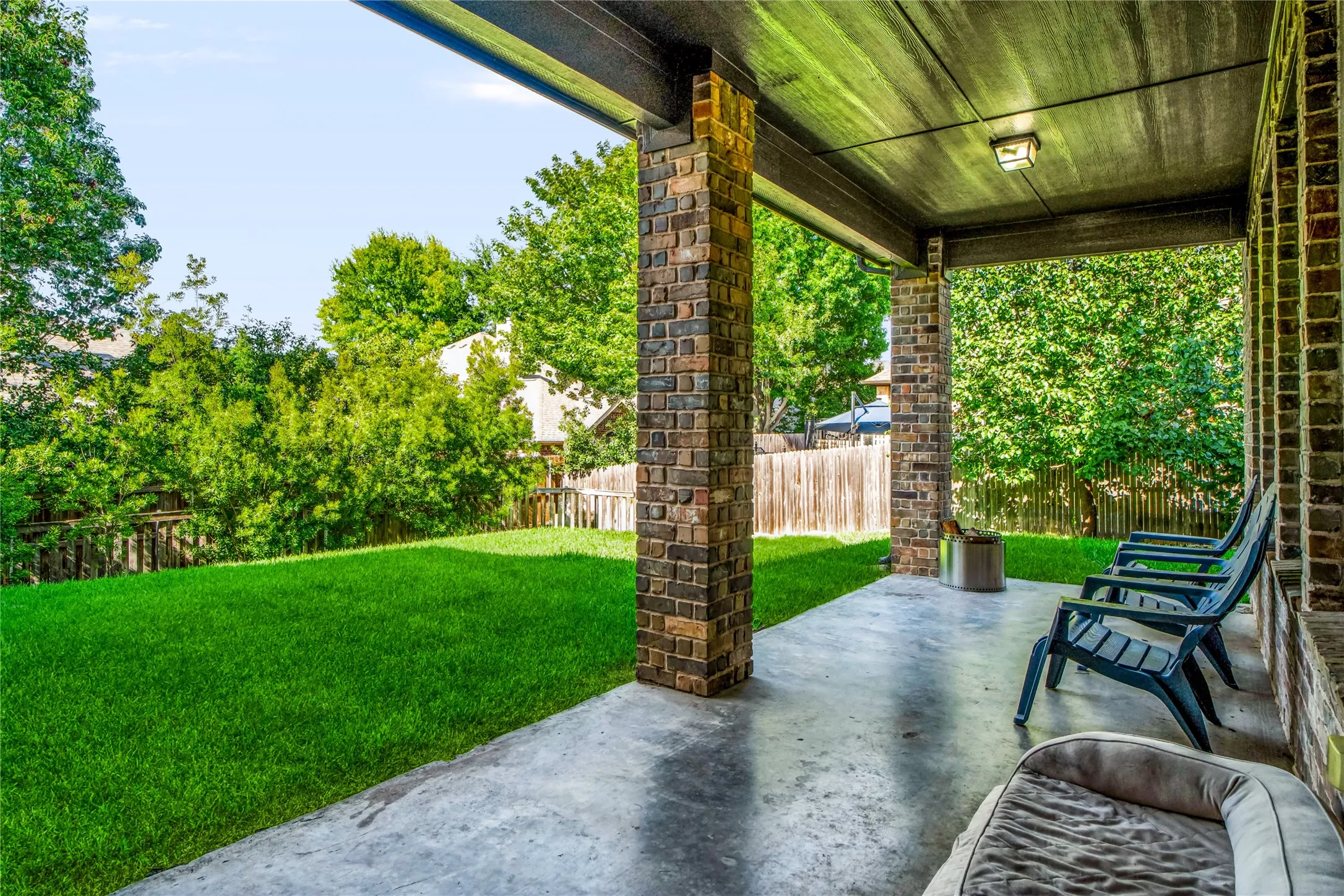 Covered patio with a concrete surface, brick columns, and a wood-finish ceiling