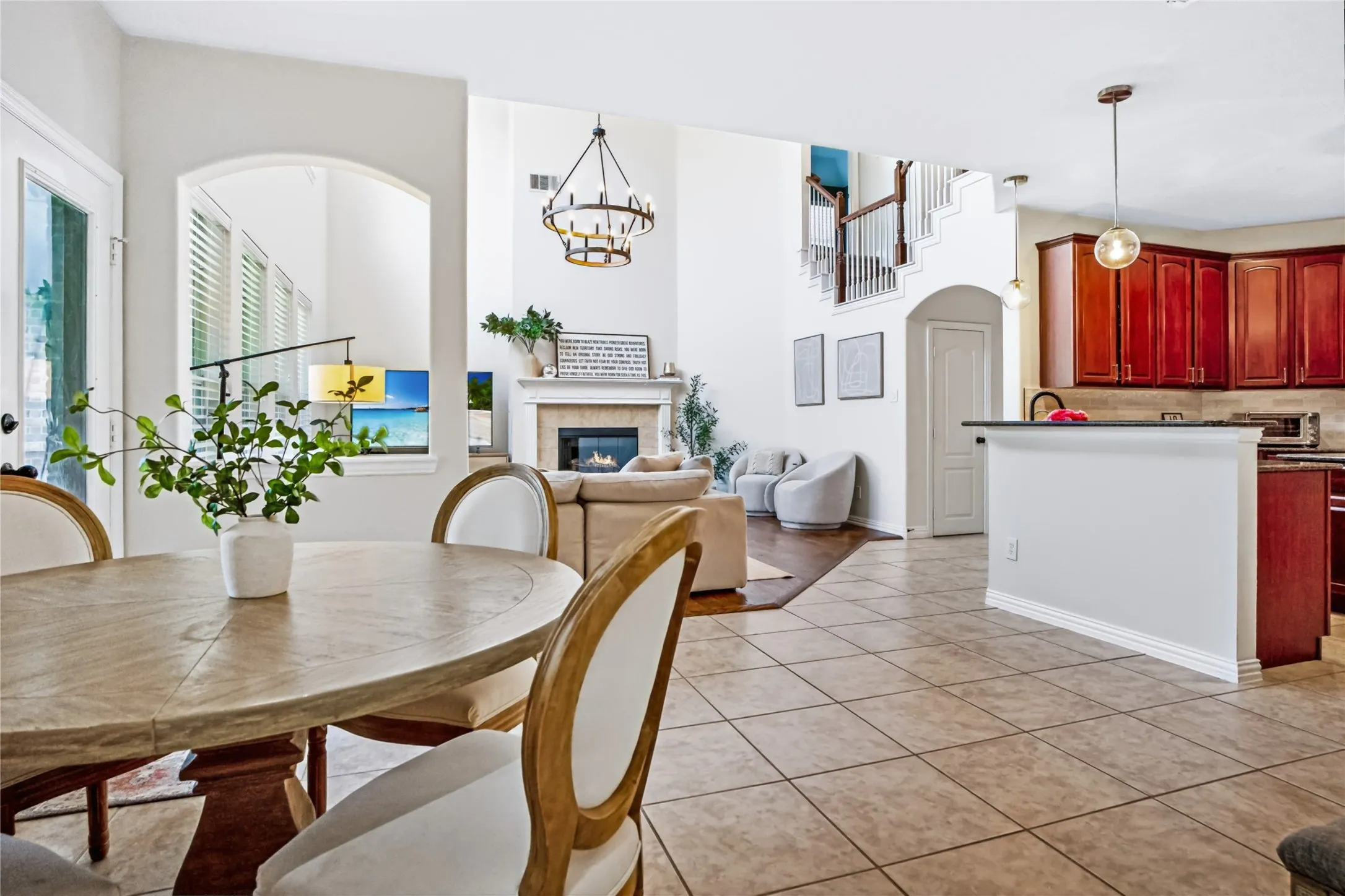 Open-concept living area with high ceilings, a fireplace, and a prominent staircase