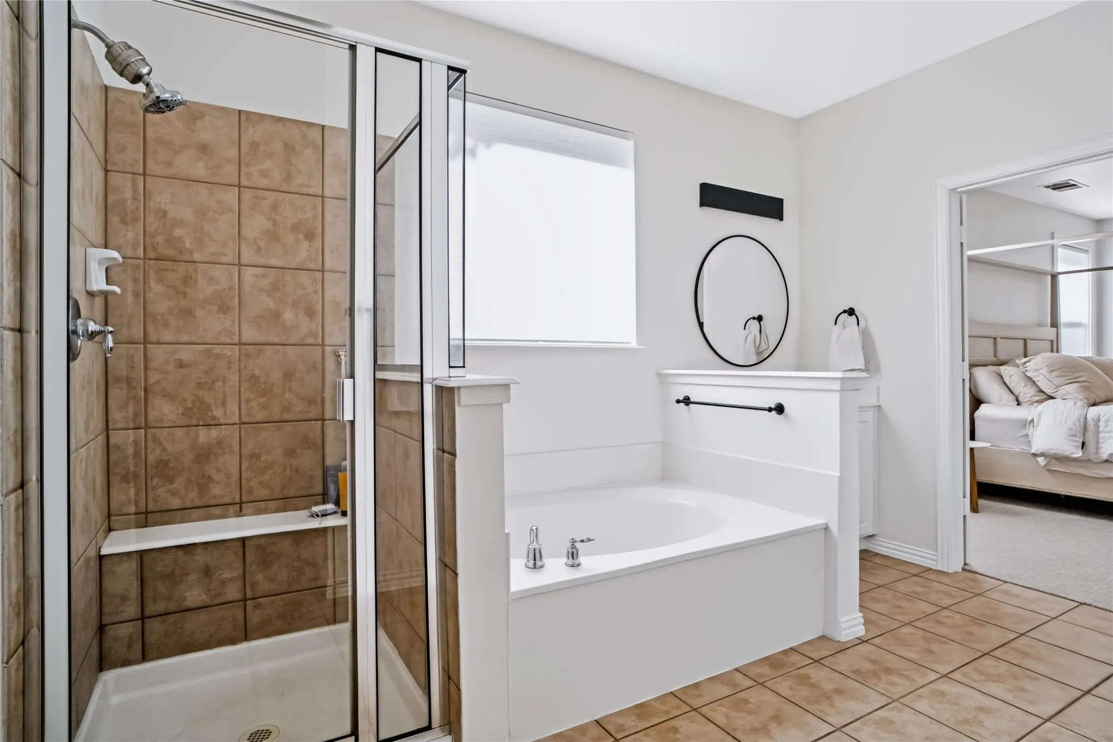 Tile flooring, built-in soaking tub, separate shower with glass enclosure, tiled shower walls with built-in bench, and a privacy window