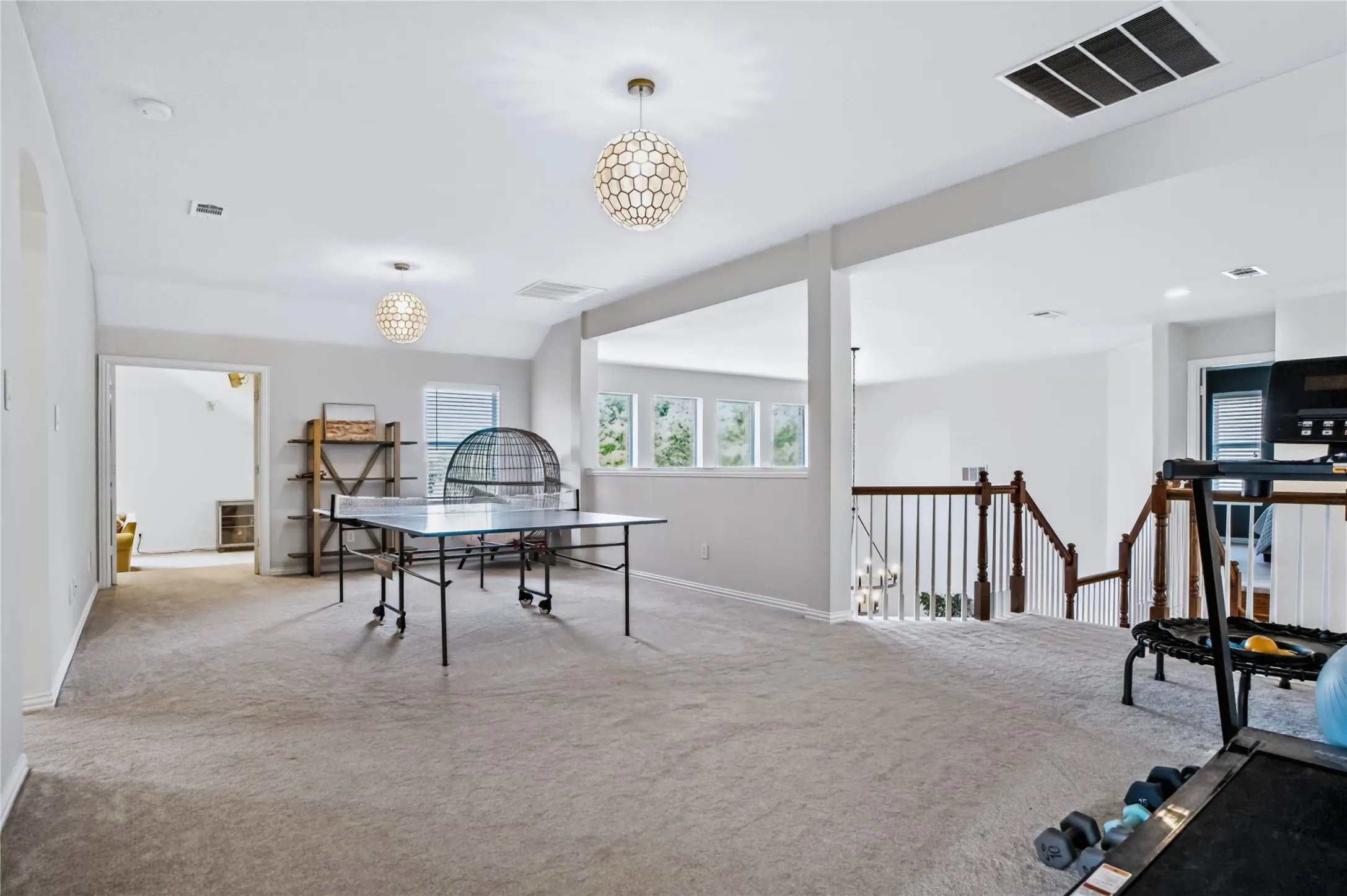 Spacious room featuring carpeting, multiple windows, and two decorative pendant light fixtures