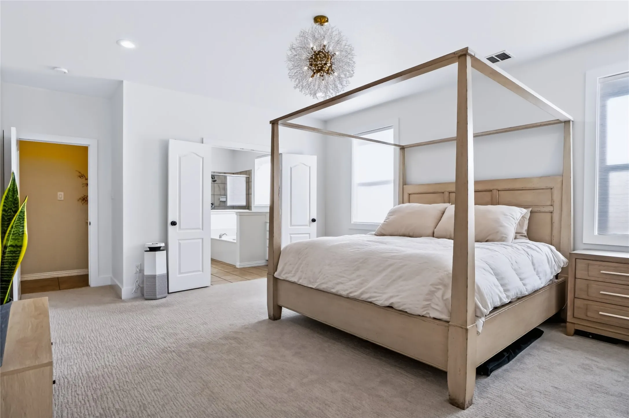 Recessed lighting, large windows, a decorative chandelier, and light-colored carpeting