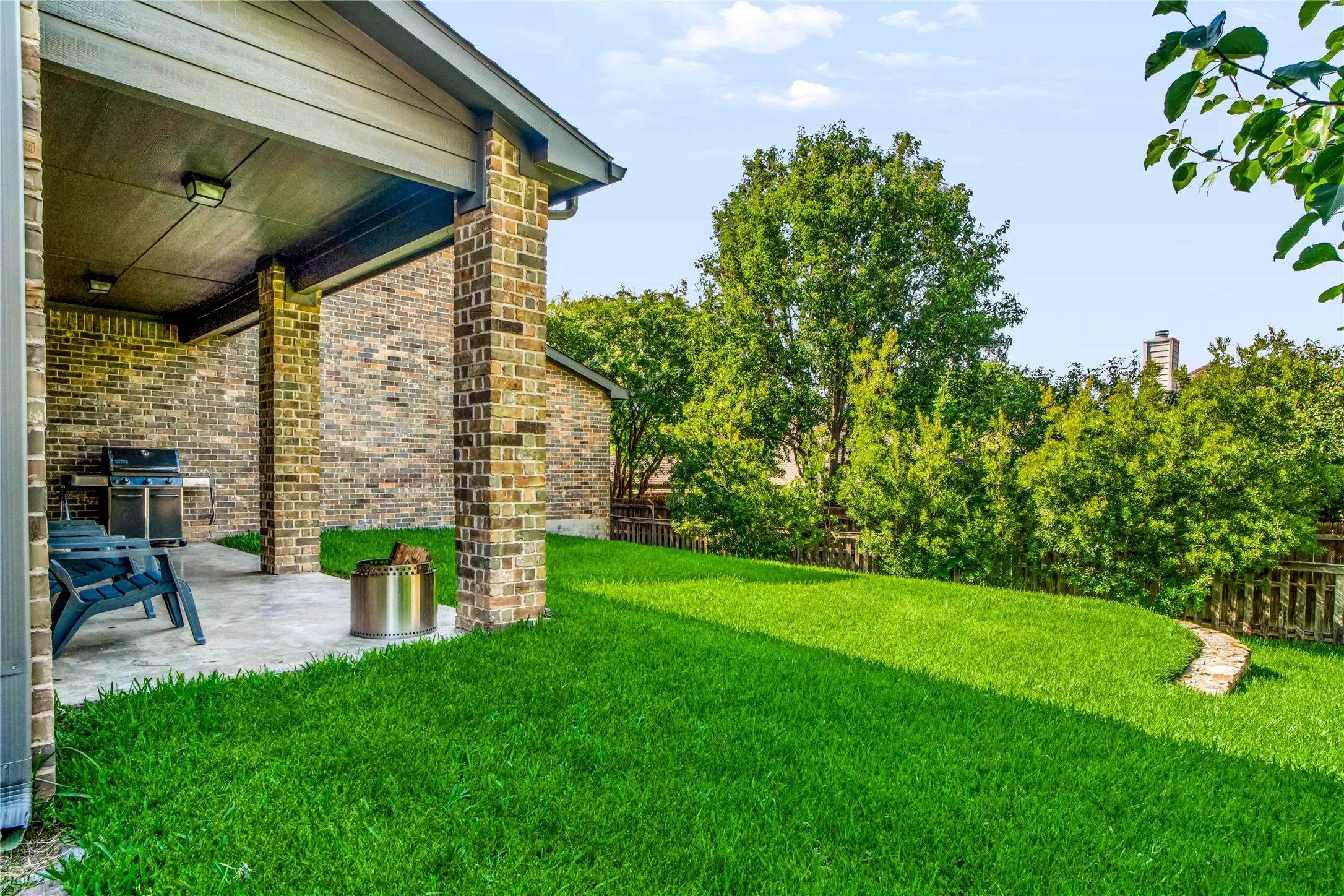 Expansive outdoor patio with brick columns, brick exterior, and concrete flooring