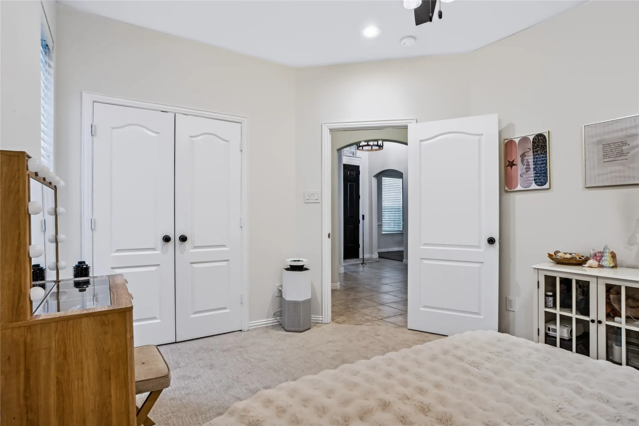 White paneled doors with black hardware, arched entryway, and neutral wall tones