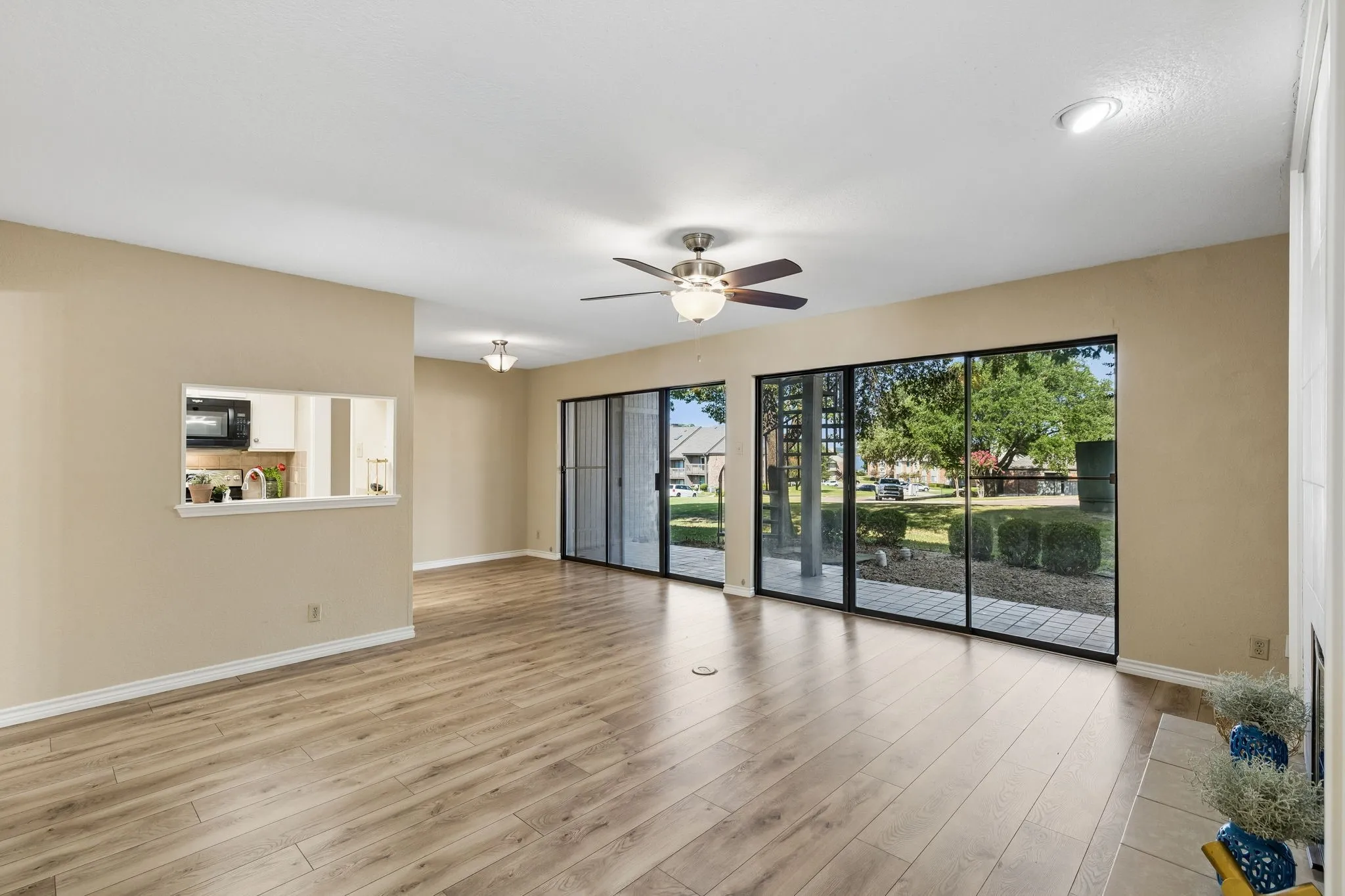 Spacious open-concept living area flooded with natural light through expansive sliding glass doors and windows overlooking manicured landscaping