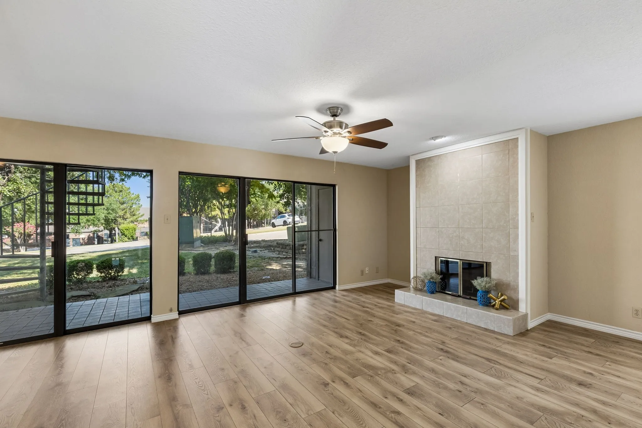 Spacious living area featuring expansive sliding glass doors, ceiling fan and a fireplace