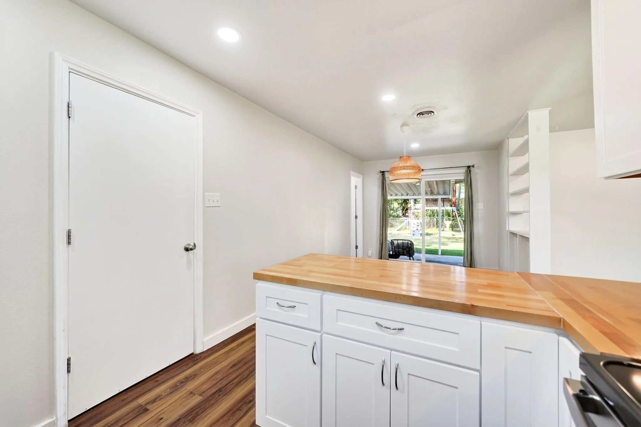White shaker-style cabinetry with wood-finish countertops, wood-finish flooring, recessed lighting, and built-in shelving