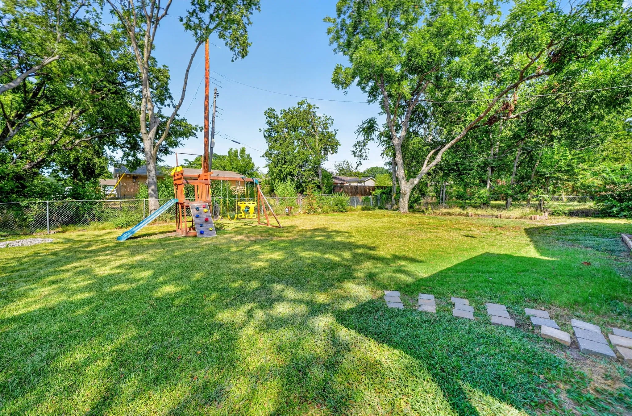 Expansive lawn area with mature trees and stepping stone pathway