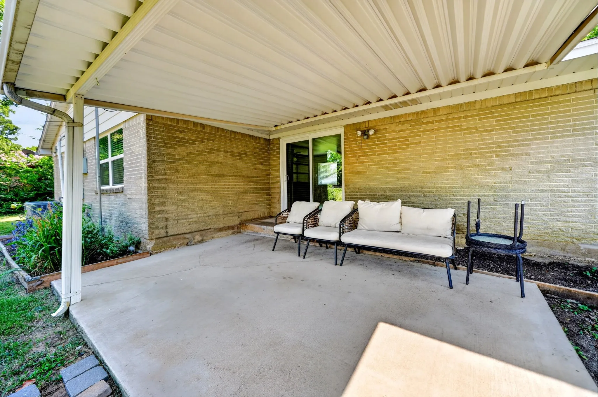 Covered patio with concrete surface, brick exterior, and sliding glass door access
