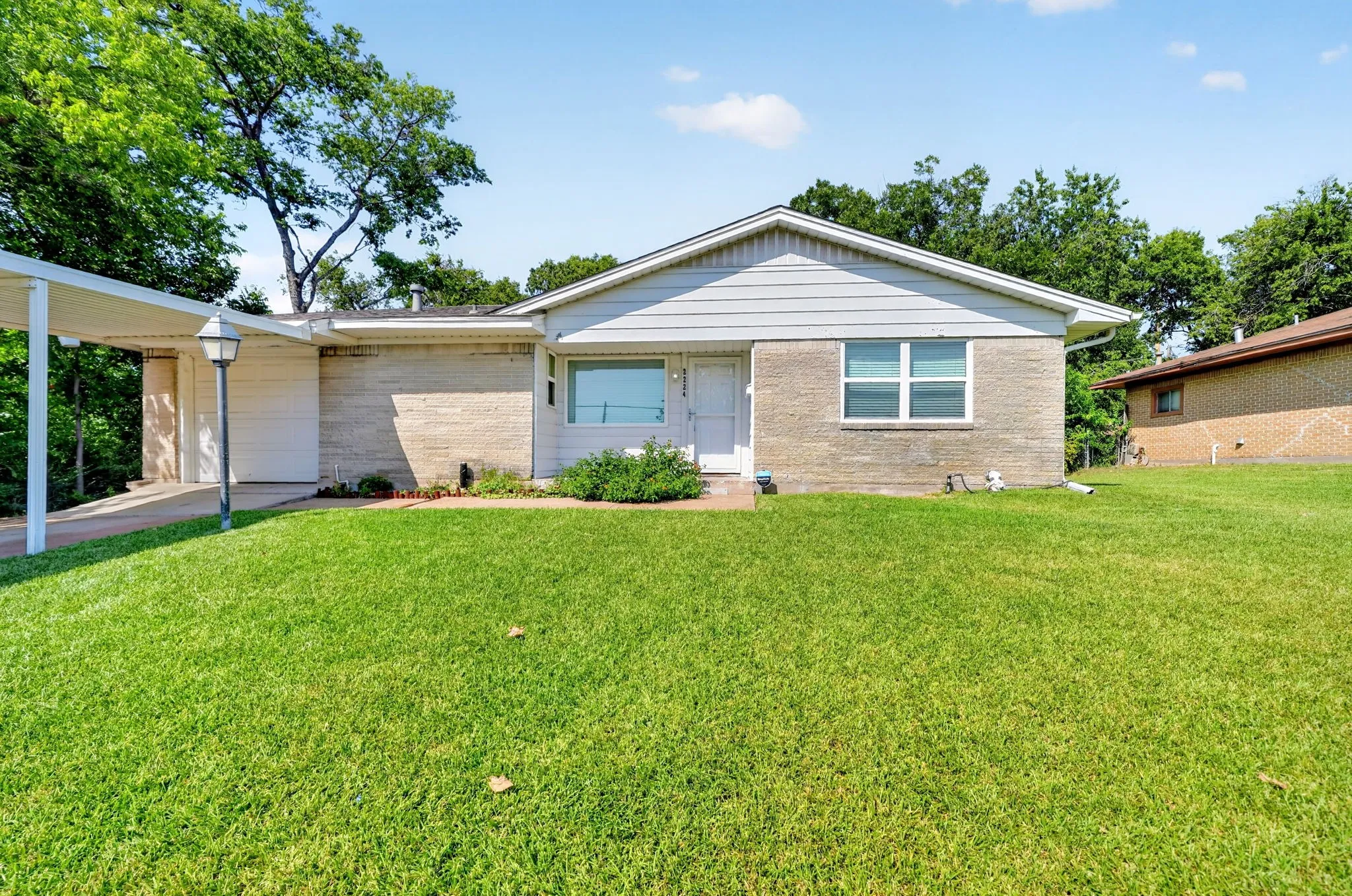 Brick and siding exterior with a carport and an expansive front lawn