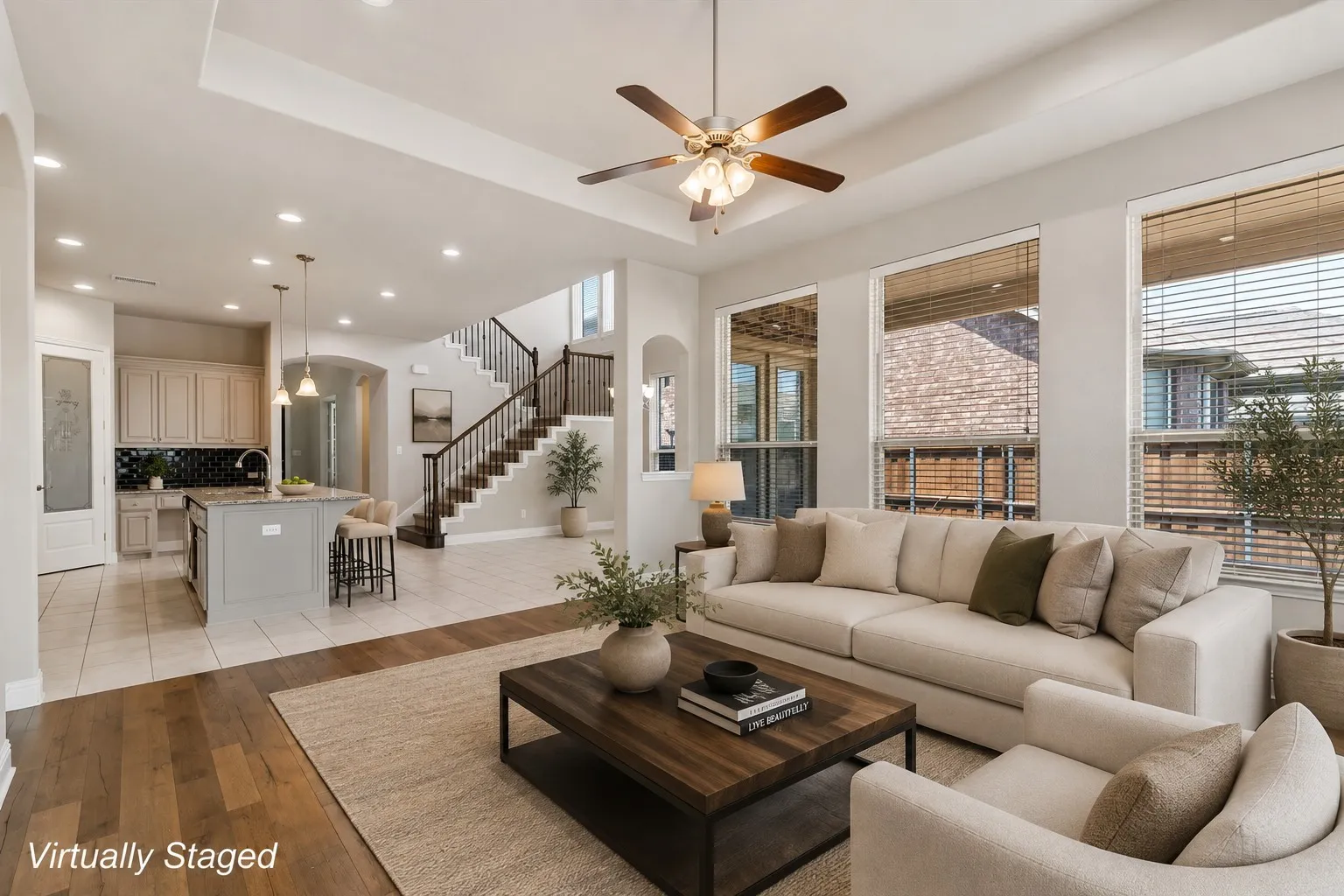 Open-concept living area featuring a cream upholstered sofa, wood-finish flooring, and a dark wood coffee table
