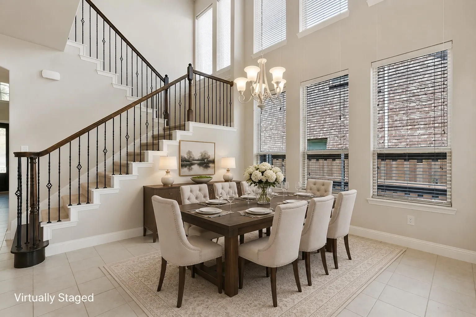 Two-story ceilings with high windows, a chandelier light fixture, iron baluster staircase, and tile flooring