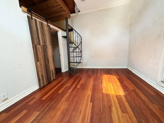 Primary bedroom showing light from skylight on the floor and metal stairway to storage area