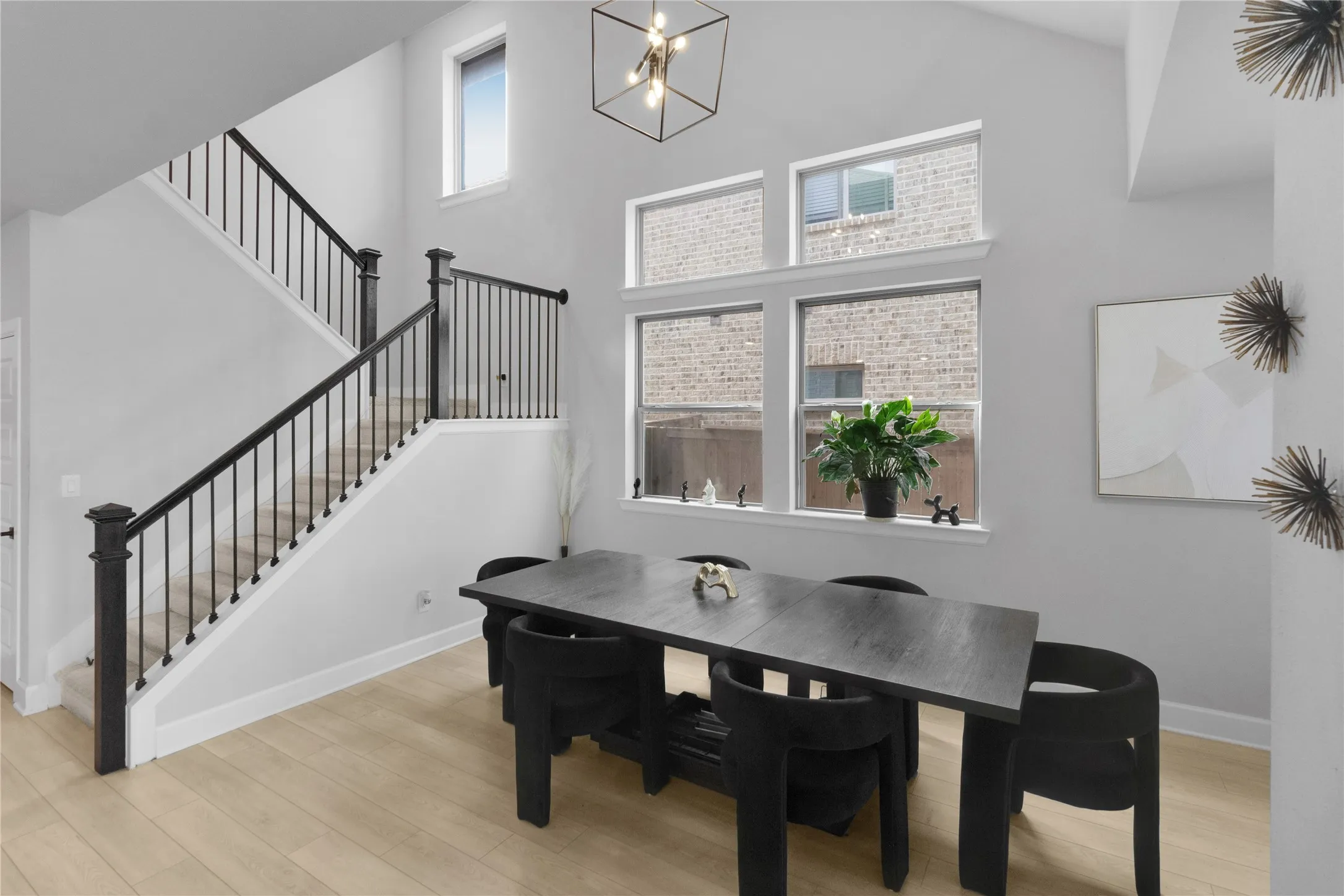 Spacious interior featuring light wood-finish flooring, a contemporary black metal and wood staircase, and multiple windows providing natural illumination