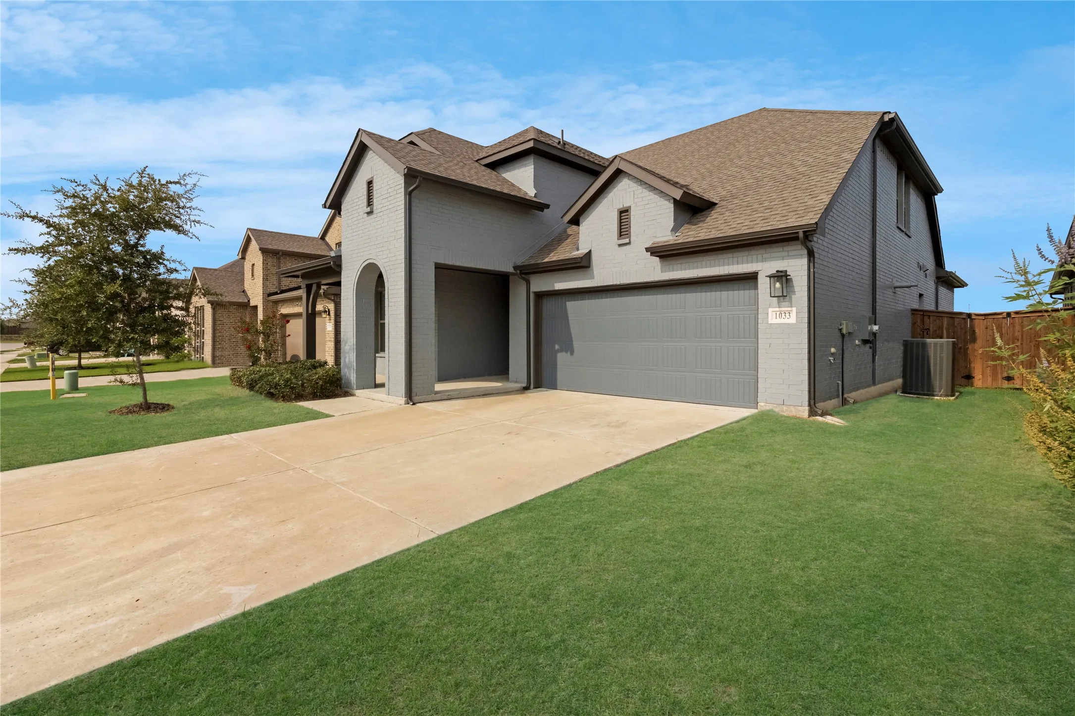 Contemporary brick exterior with gray paint, a two-car garage, and a concrete driveway
