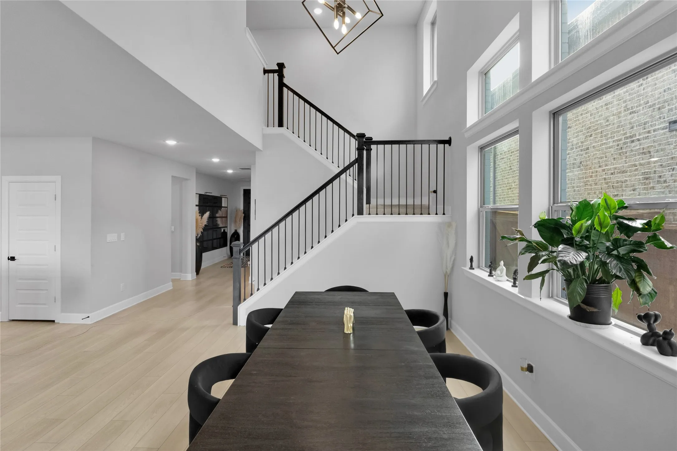 Two-story entryway featuring a contemporary chandelier, open staircase with black railings, and wood-finish flooring
