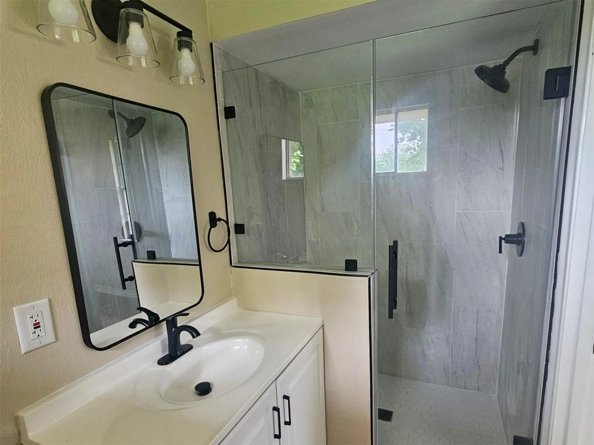 Modern bathroom featuring a glass-enclosed shower with large format tile surround and a tiled floor