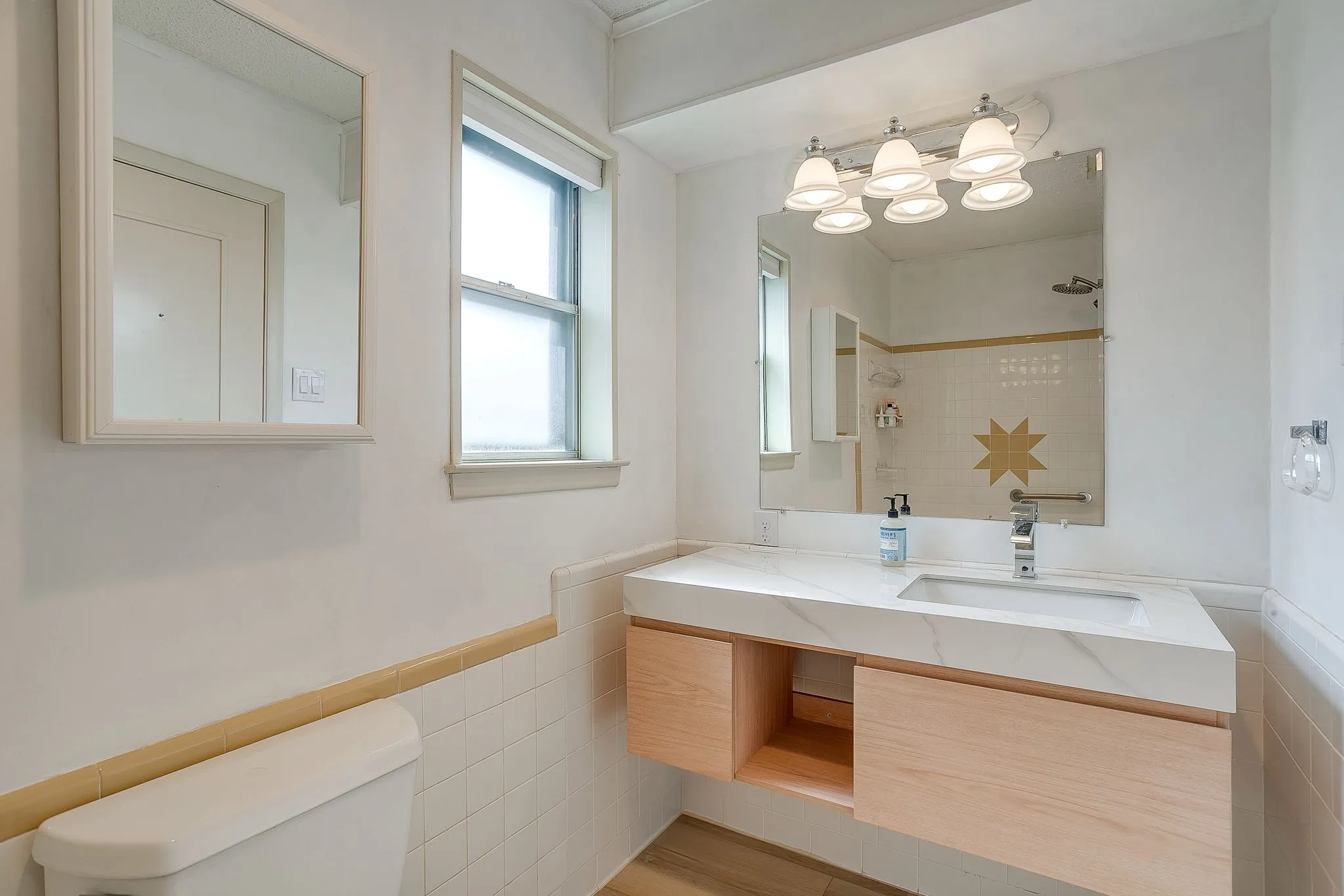 Floating vanity with a built-in rectangular sink and a polished chrome faucet, under a wall-mounted light fixture