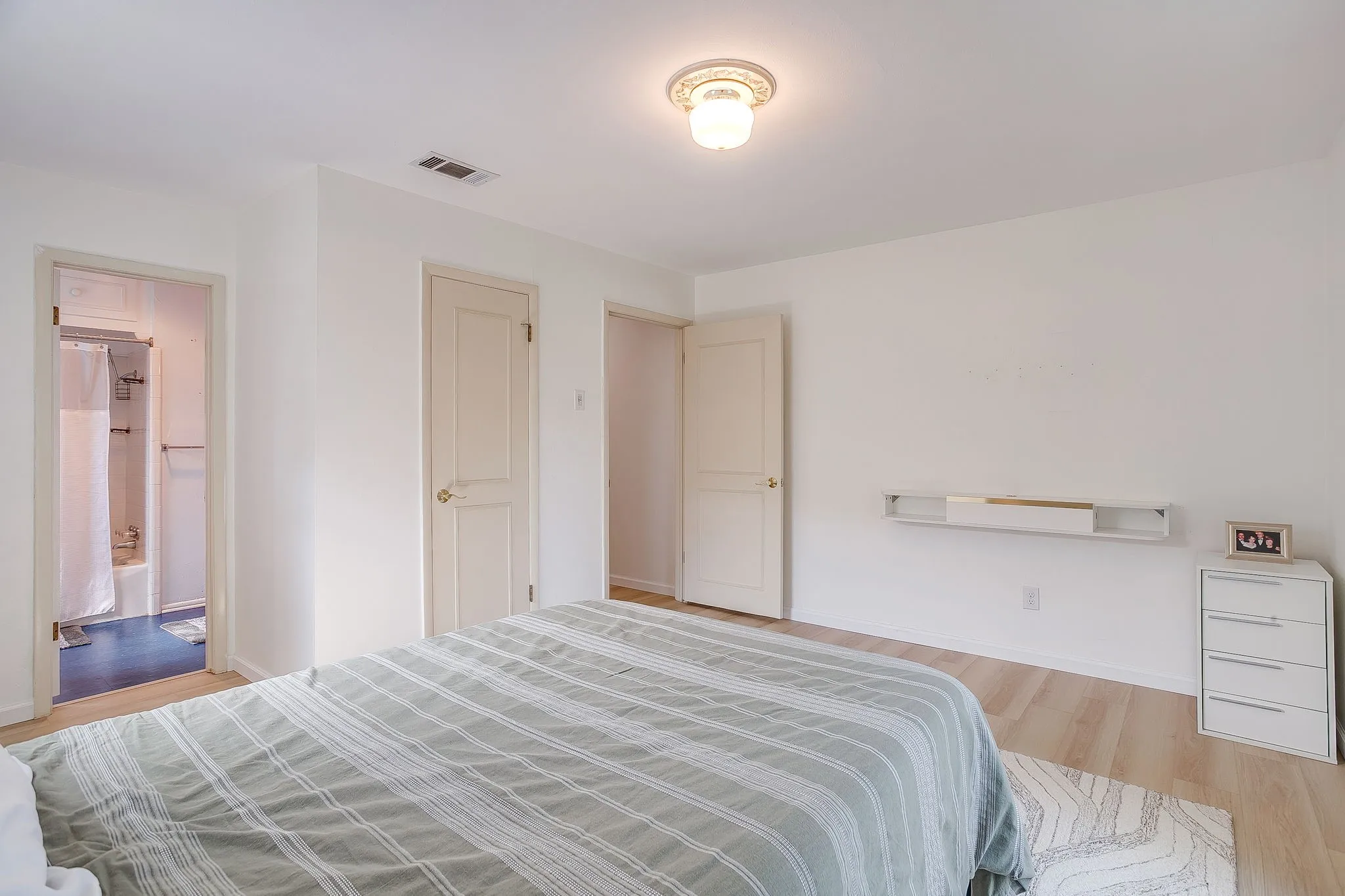 Light wood-finish flooring, white walls, and a ceiling-mounted light fixture