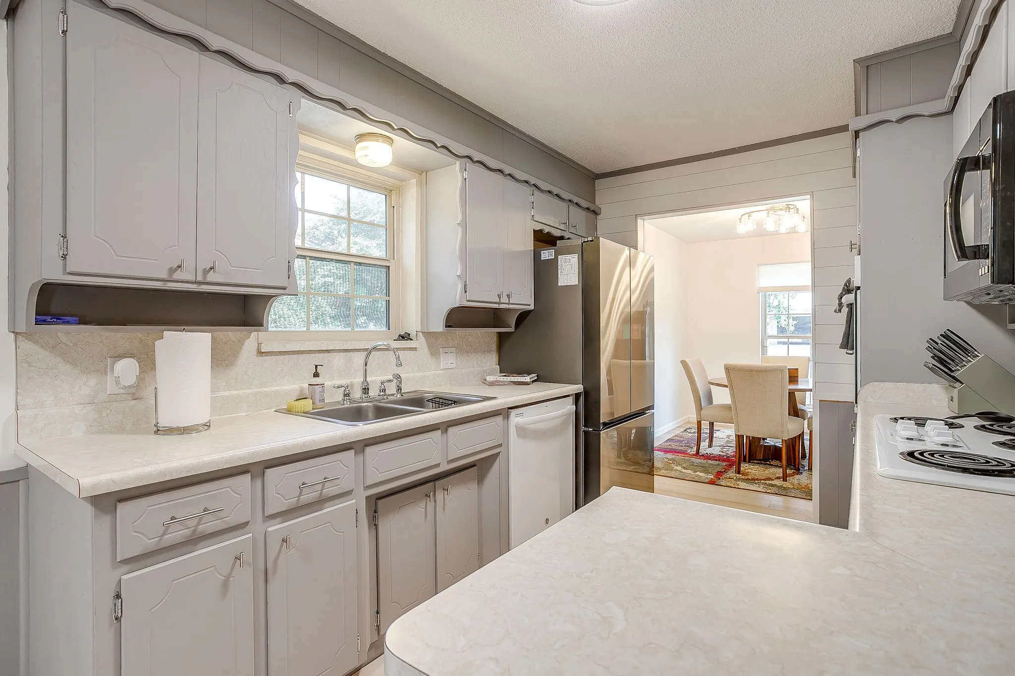 Kitchen featuring light gray cabinetry, white countertops, a double basin sink, and a built-in microwave