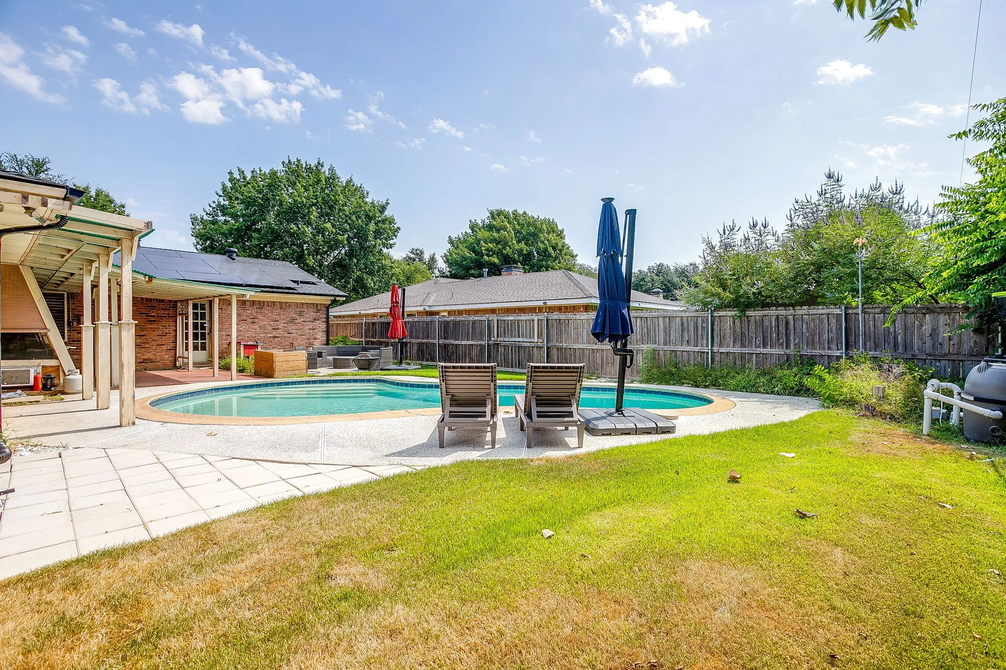 Swimming pool with surrounding concrete patio and adjacent grass area