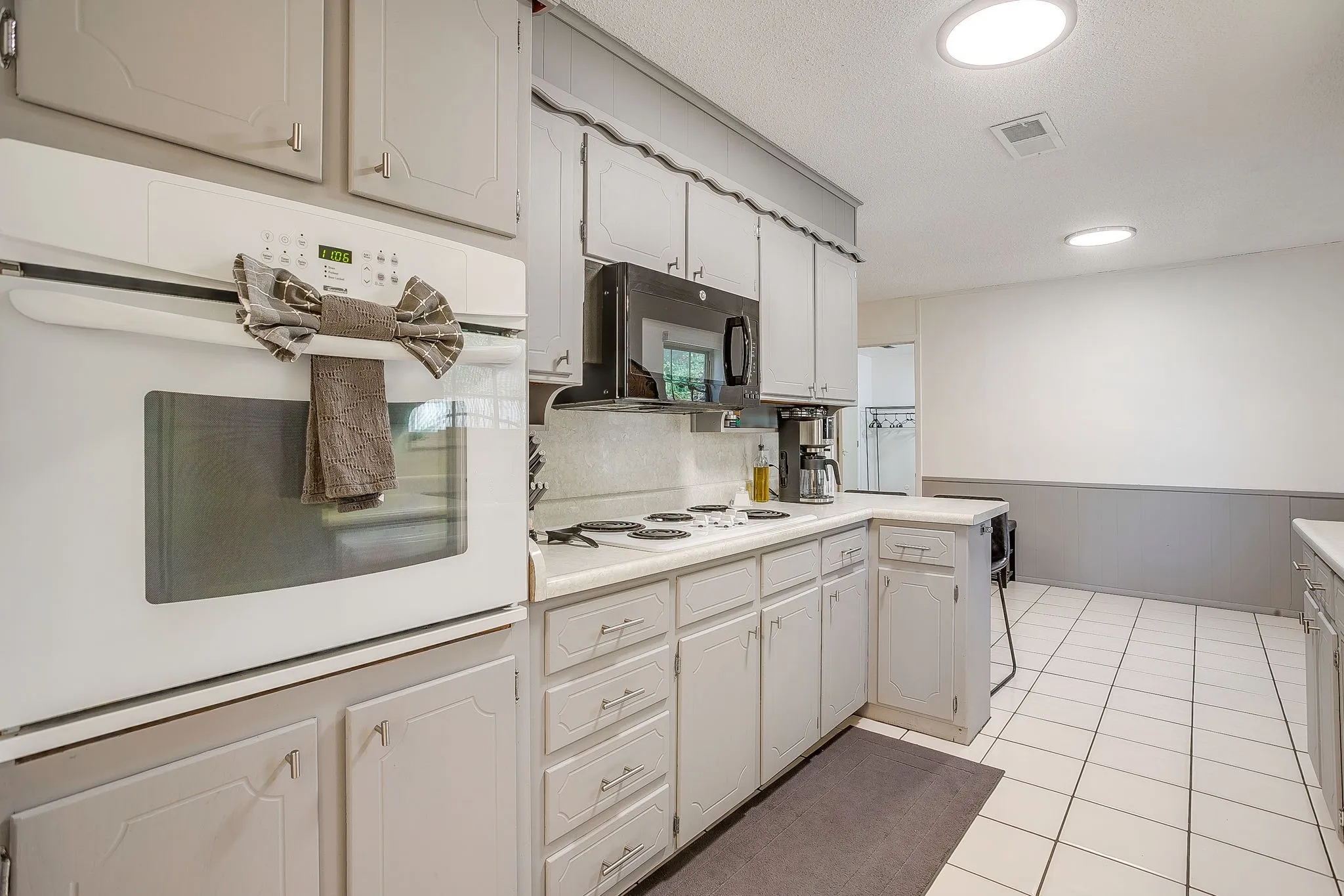 White tile flooring, built-in oven, overhead microwave, recessed lighting, and ample cabinetry