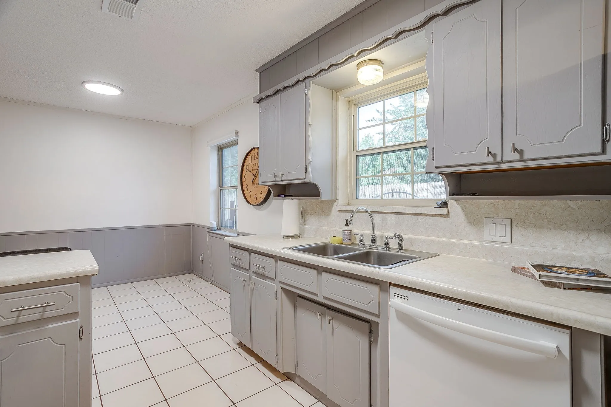 Tile flooring, painted cabinetry, dual basin sink, integrated dishwasher, and a window for natural light