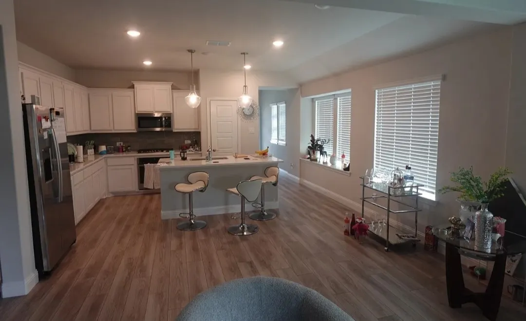 Open-concept living space with wood-finish flooring, recessed lighting, and multiple windows