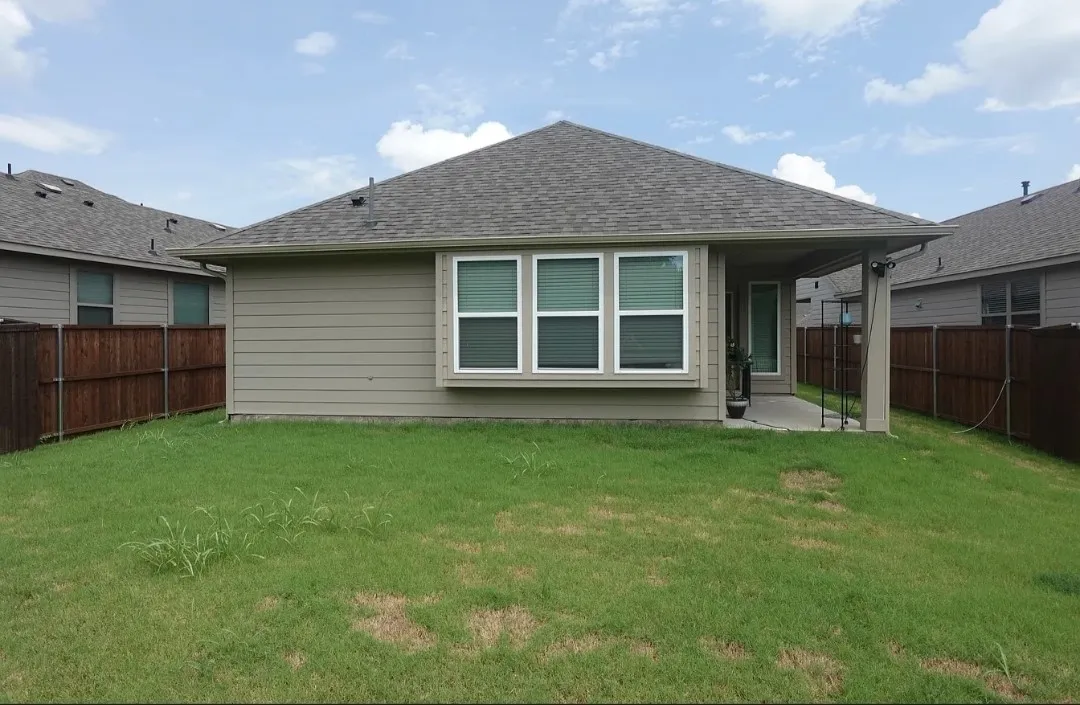 Expansive backyard with a covered patio, privacy fencing, and a bay window