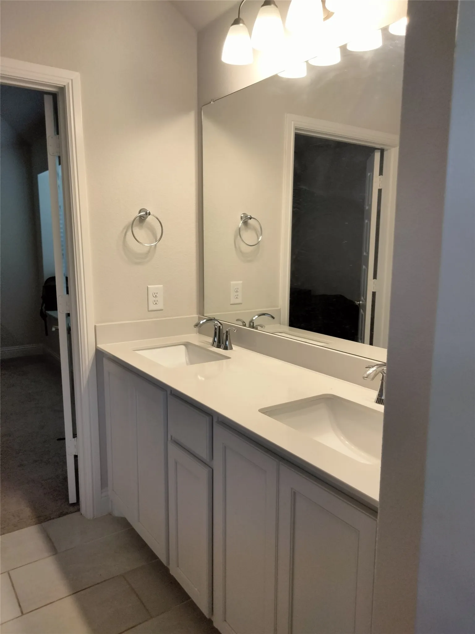 Dual undermount sinks with chrome fixtures, light-toned countertop, and white cabinetry