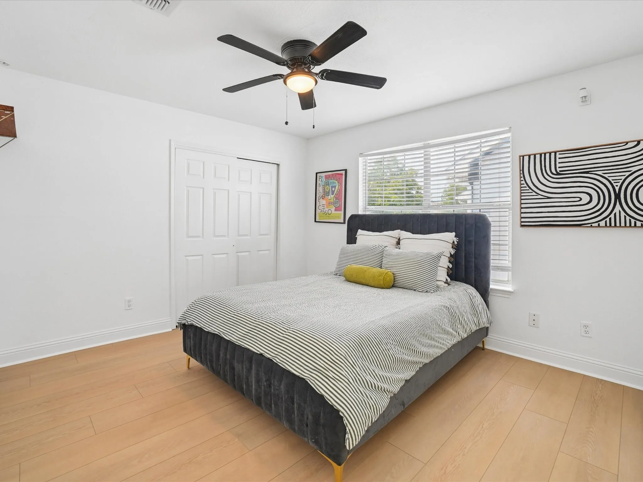 Bright interior with wood-finish flooring, a ceiling fan, and a window with horizontal blinds