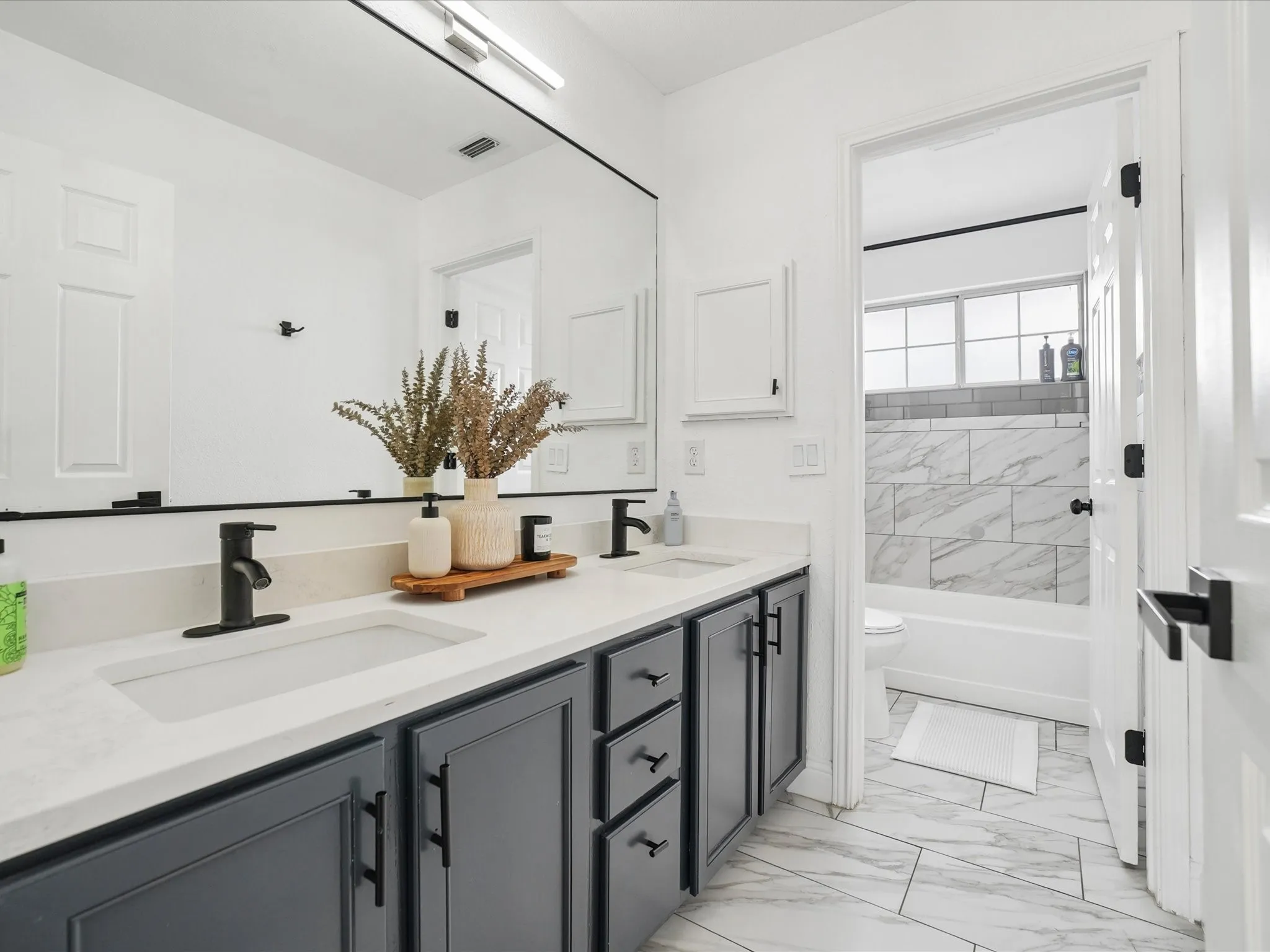 Dual vanity with black hardware and light countertop