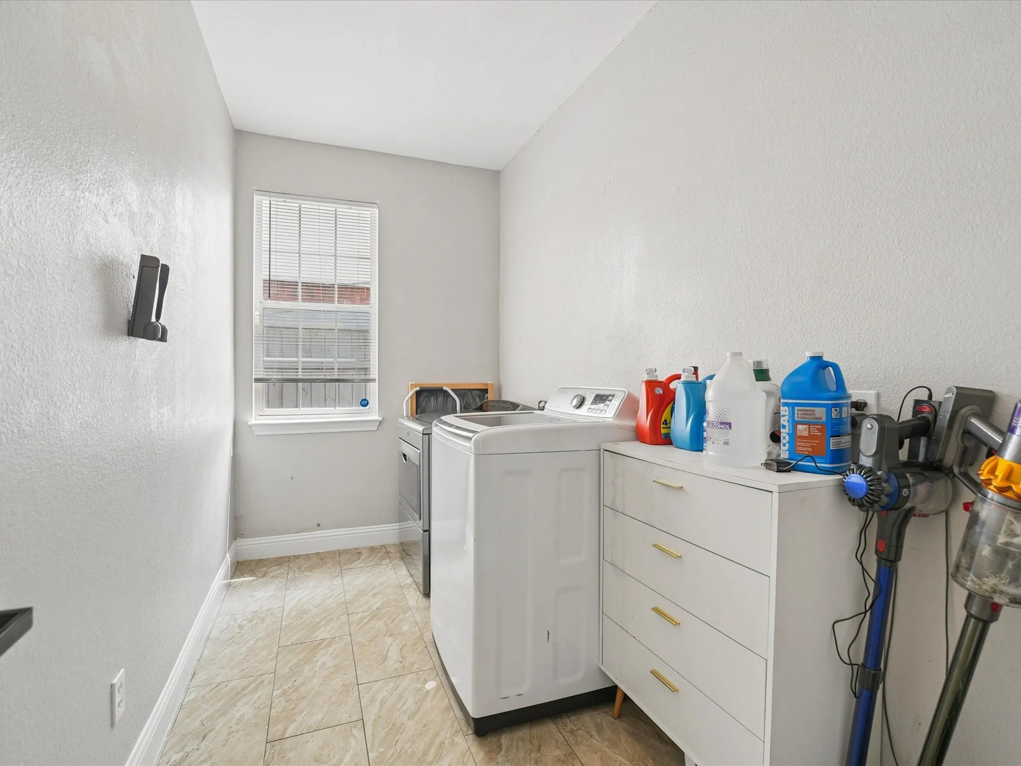 Dedicated utility room featuring tile flooring, a window with horizontal blinds, and light-toned walls