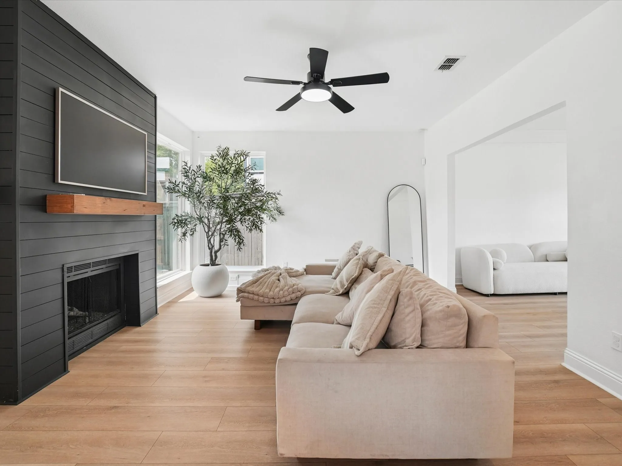 Living area featuring a modern fireplace with a black shiplap surround, a wooden mantel, and wood-finish flooring