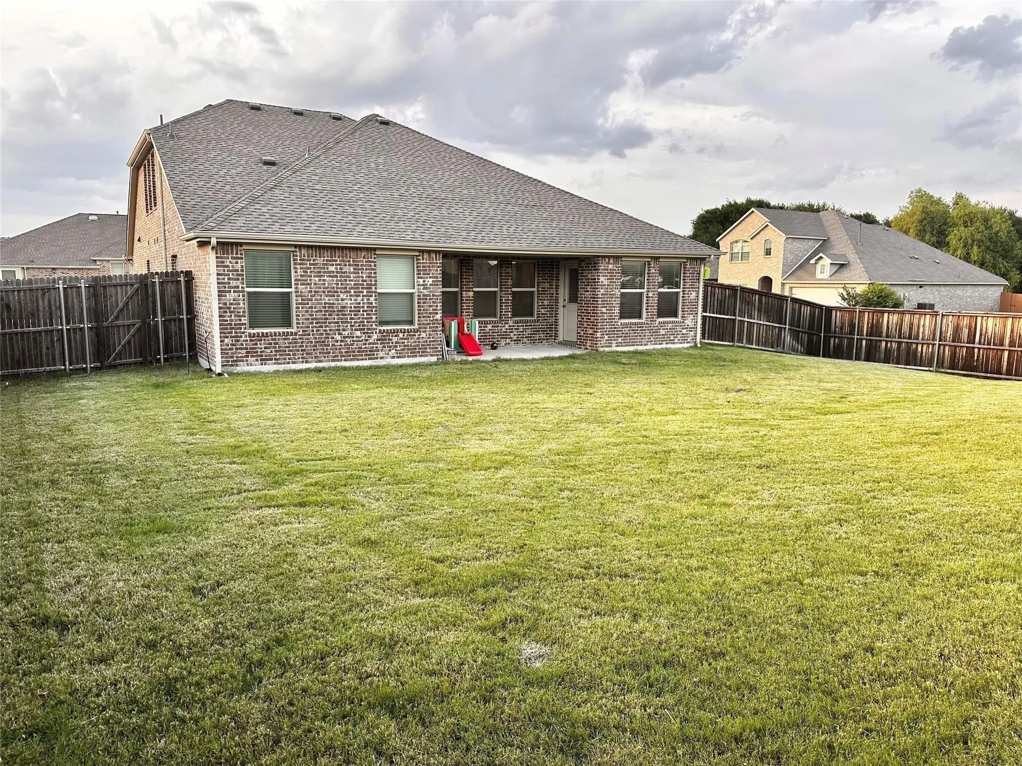 Generous backyard retreat offering a large grassy area, privacy fencing, and plenty of space for gatherings, pets, and outdoor enjoyment.