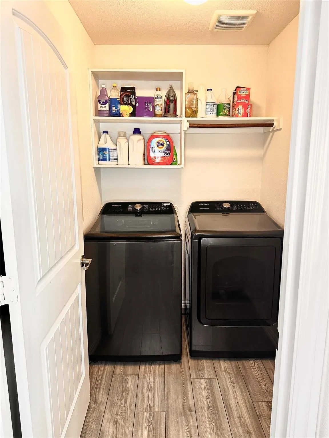 Dedicated laundry area featuring durable wood-look flooring and practical space for organization and storage.