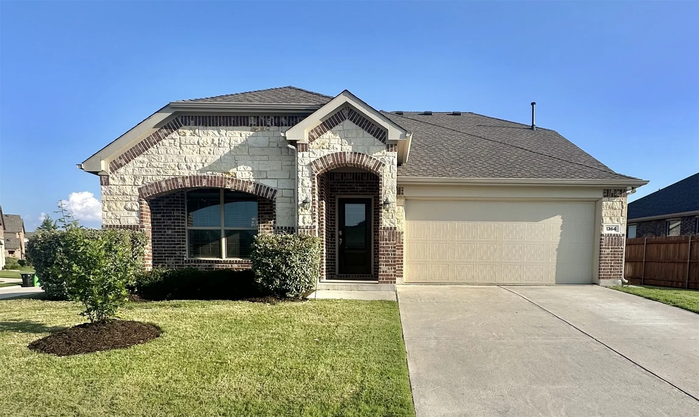 The primary image for this listing showcases the elegant and well-maintained front of structure, highlighting the home's overall curb appeal and architectural design as seen from the street level as it features brick and stone, 2 car garage & a long driveway for extra cars to be parked in the drive way & not on the streets.