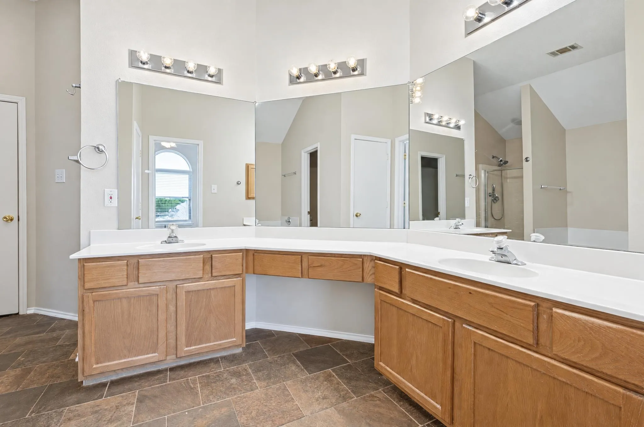 Spacious primary bathroom featuring dual sinks, a relaxing garden tub, separate shower, and a generous walk-in closet, offering comfort and convenience.