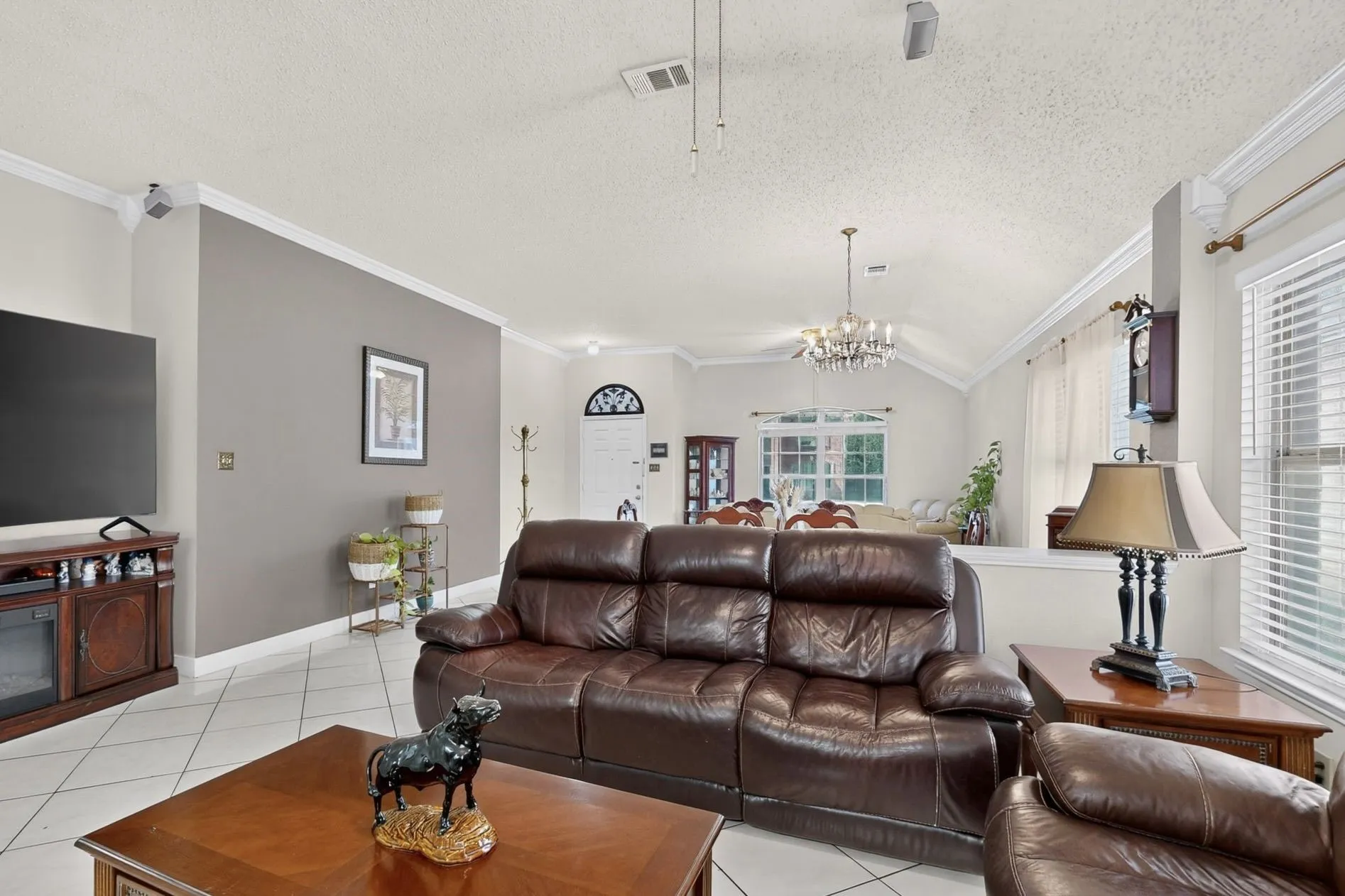 Expansive living area featuring vaulted ceilings, crown molding, and tile flooring