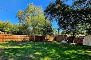 Expansive green lawn with a privacy fence, mature trees, double gate and a storage shed.
