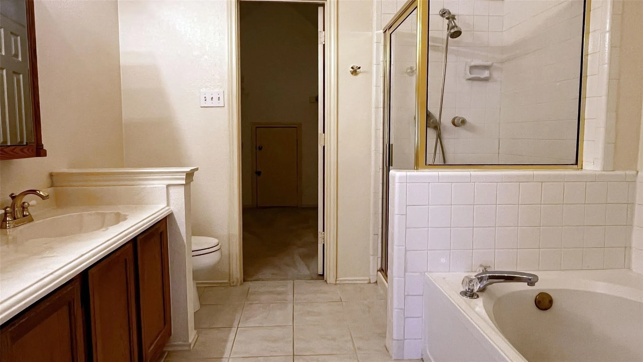 Tile flooring, vanity with integrated sink, built-in bathtub, glass-enclosed shower, and white tiled walls