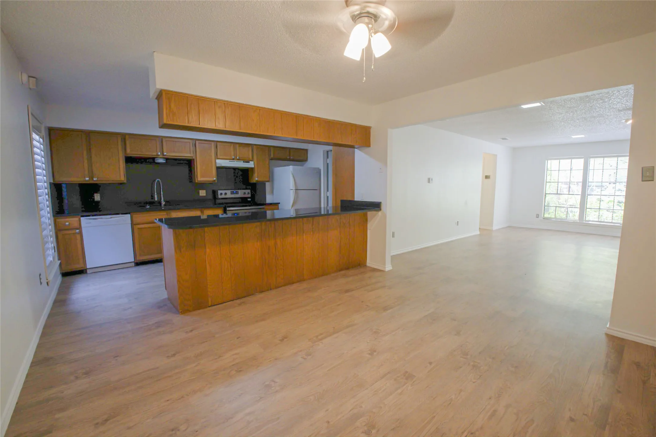 Kitchen with wood-finish cabinetry, dark countertops, and a breakfast bar